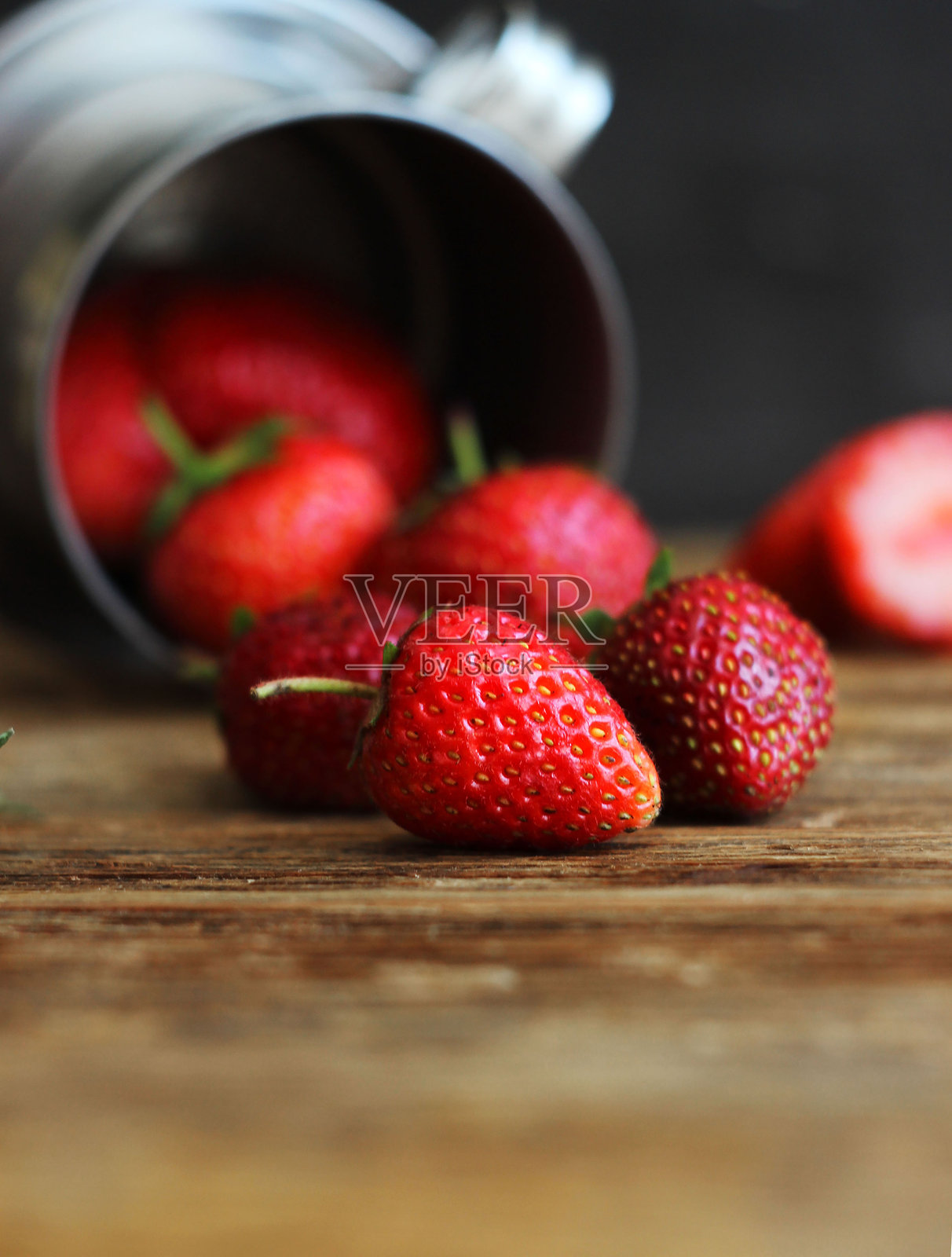 桌子上的金属桶里装着草莓照片摄影图片
