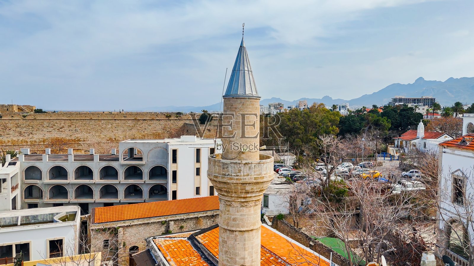 基尔尼亚北塞浦路斯的阿迦·贾费尔·帕夏清真寺及周边历史城区的鸟瞰图，尖塔在地中海建筑和山脉背景中高耸，文化遗产与旅行概念照片摄影图片
