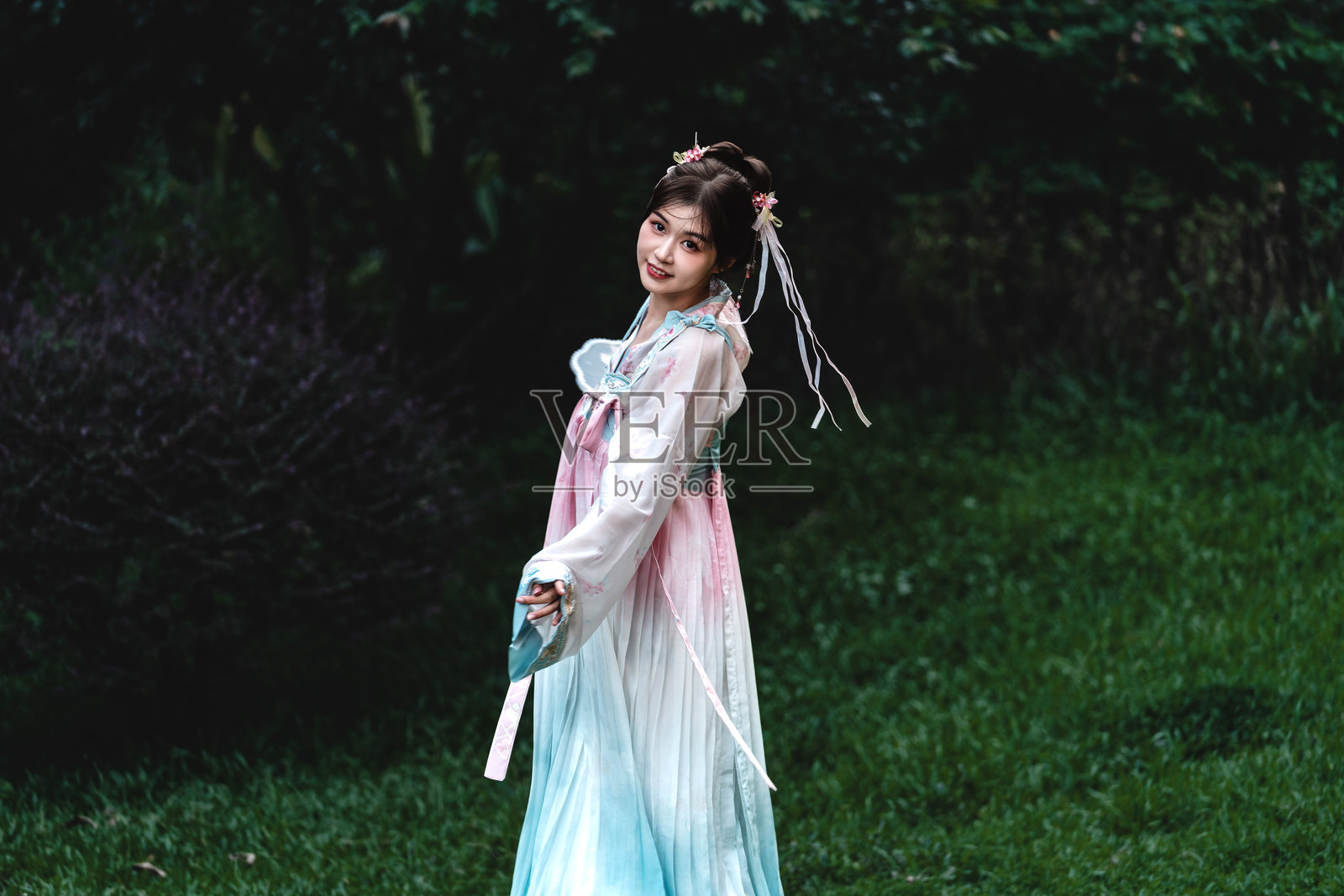 身着淡色汉服的优雅女子在古典园林中旋转，袖子和裙摆随之舞动，唤起古代中国诗歌与舞蹈的灵韵。照片摄影图片