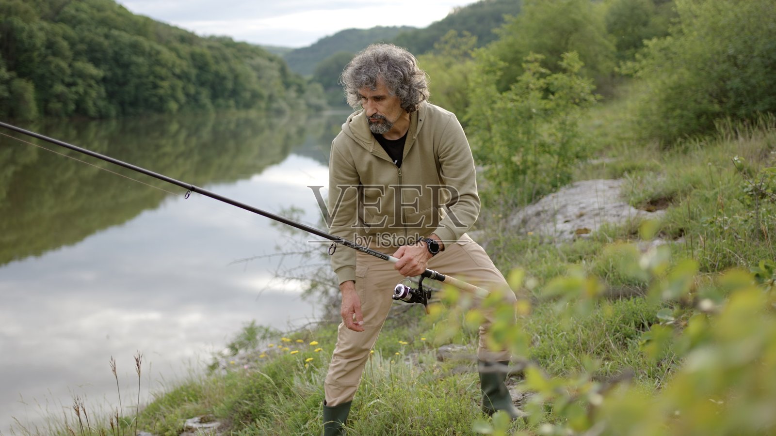 户外爱好。男人在河边放松和钓鱼照片摄影图片