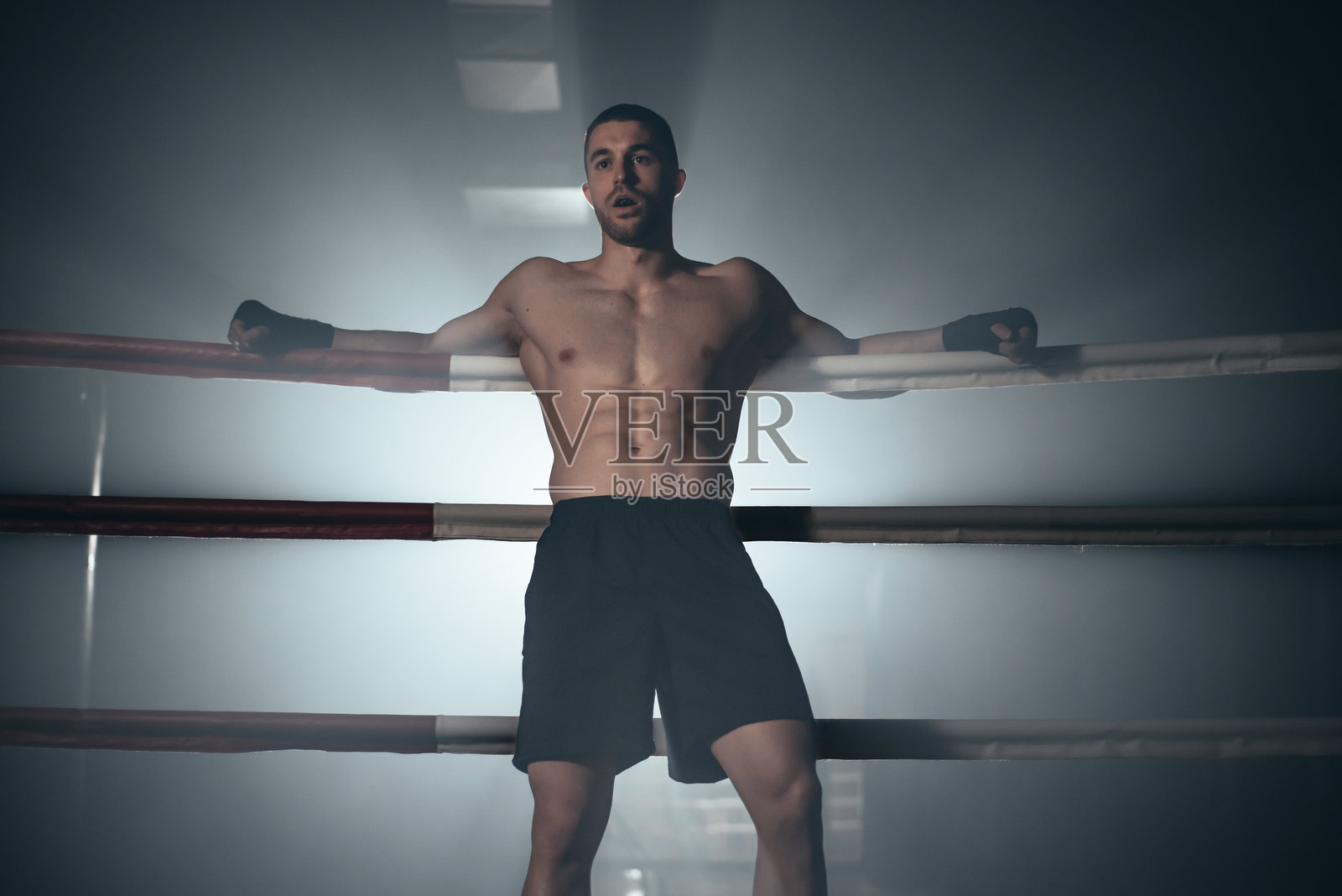 拳击手靠在拳击台的绳索上照片摄影图片