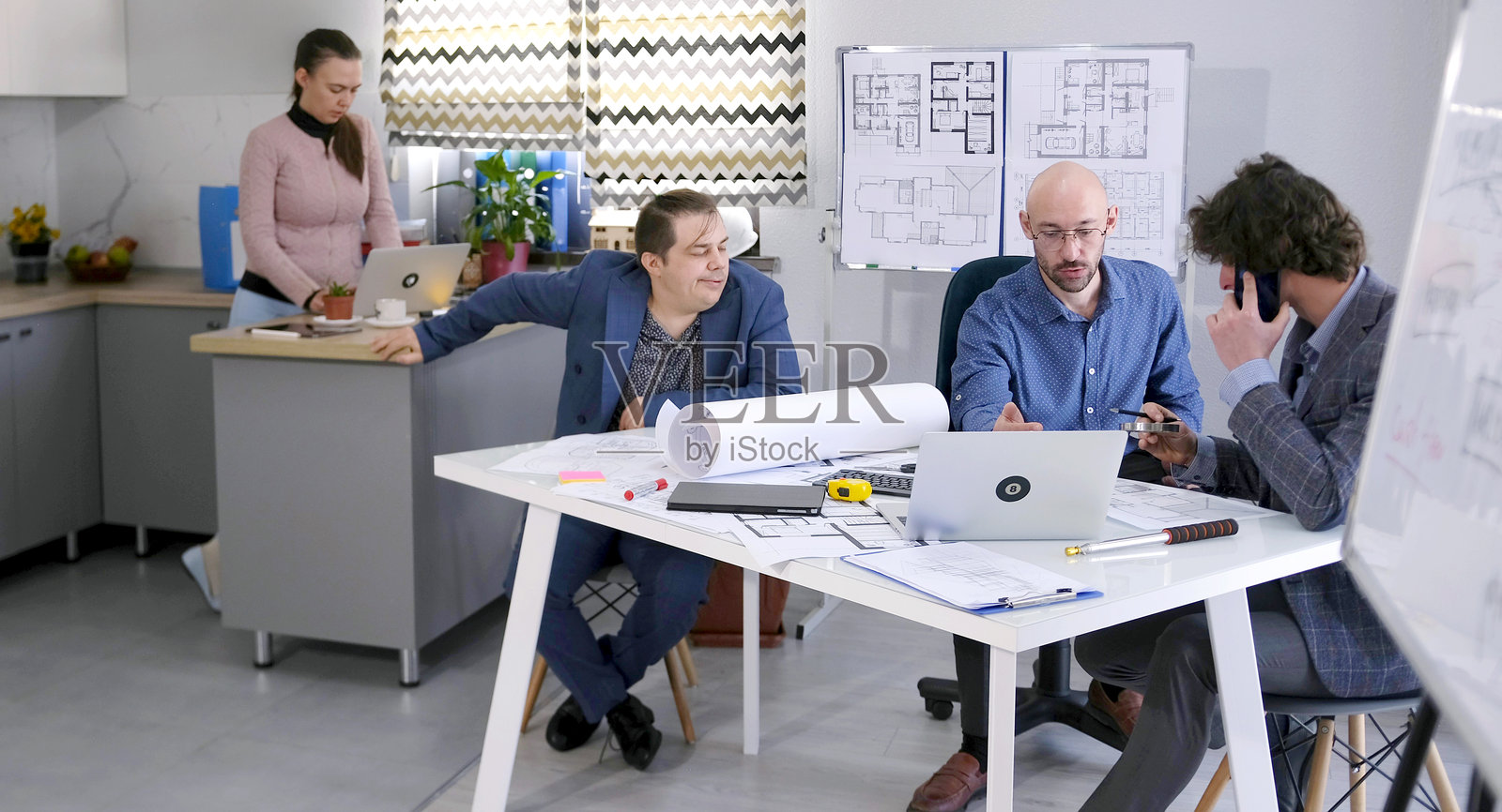 一位客户代表来到建筑事务所讨论项目预算。一小组工程师正在进行图纸的绘制。照片摄影图片