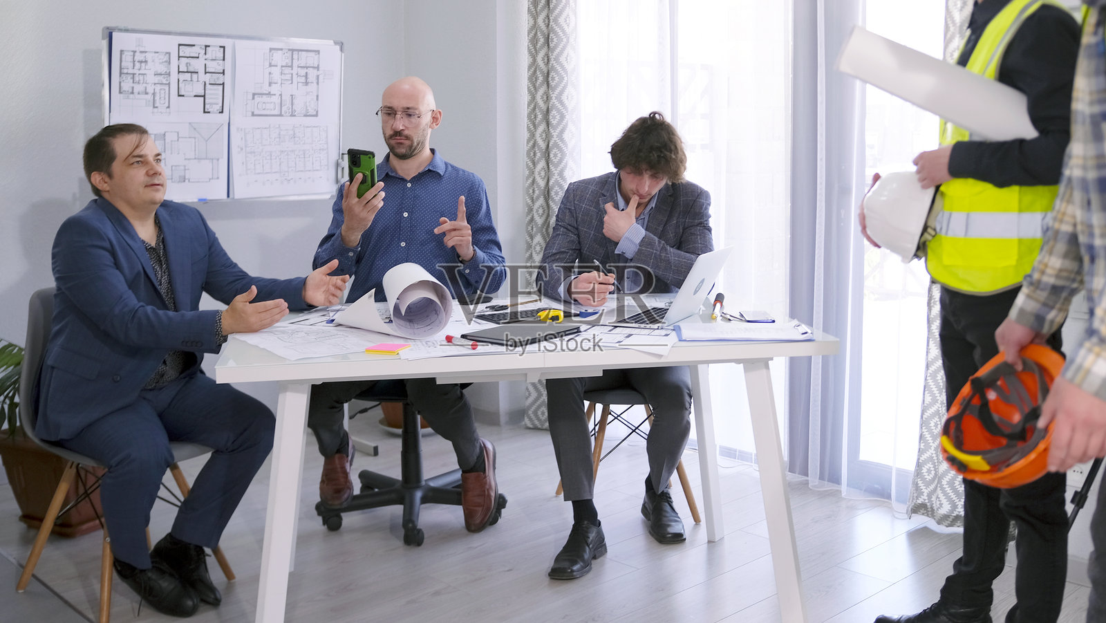 三位商人回答建筑商的问题。一群男士坐在会议室的桌子旁，讨论项目预算。照片摄影图片