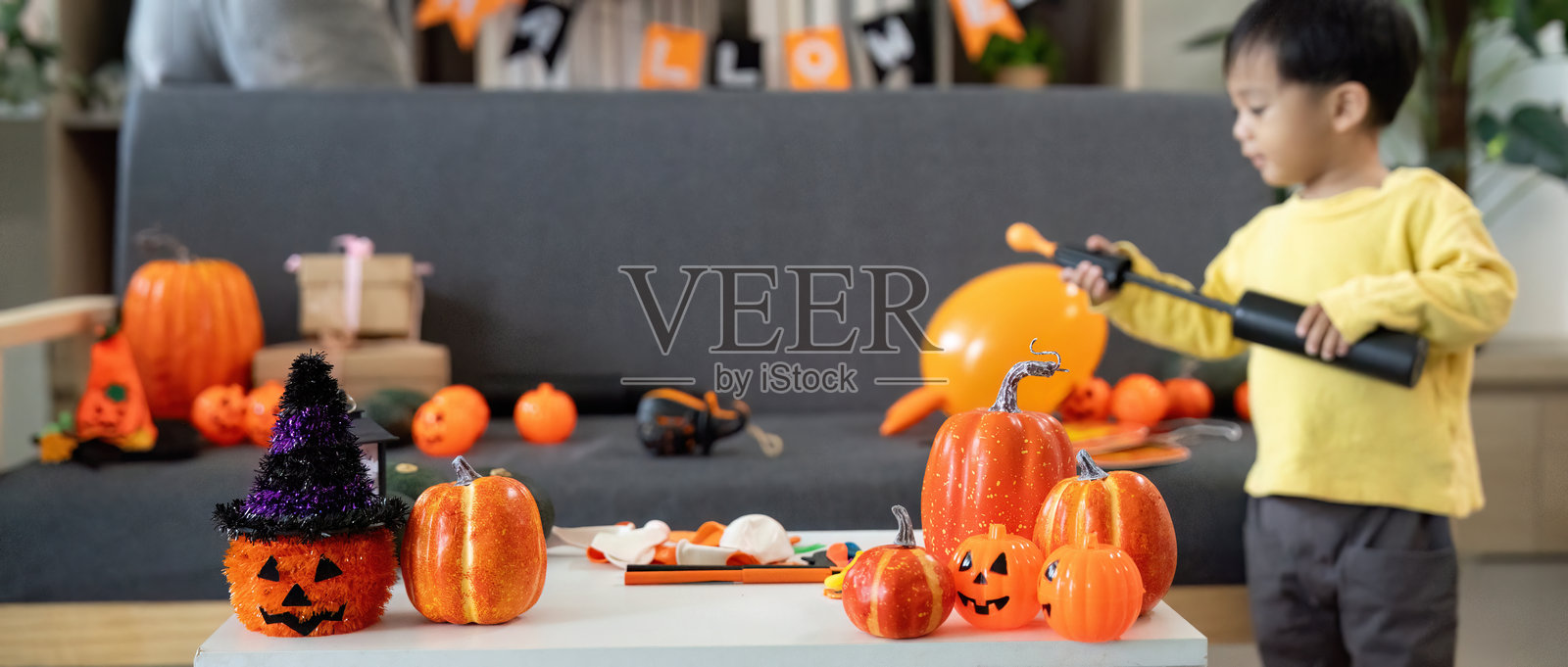 万圣节的乐趣。孩子在节日气氛中玩南瓜和装饰品。照片摄影图片