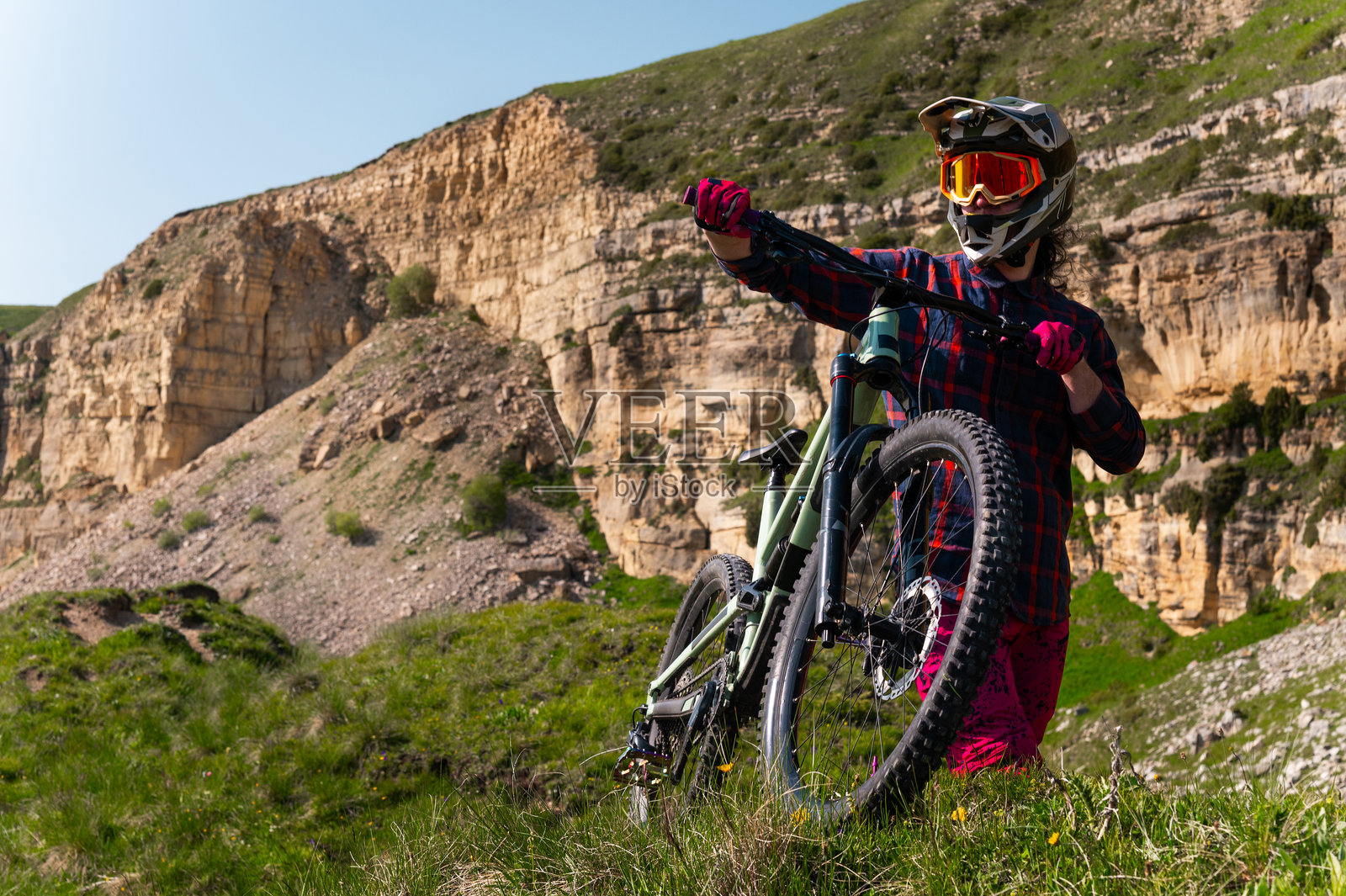 户外骑行的男子骑着山地自行车。男性游客在山中的草地小径上骑自行车，佩戴头盔和护目镜。运动、户外活动和自然概念。照片摄影图片
