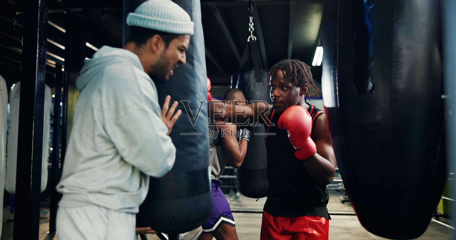 运动，男性和健身教练在健身房，拳击沙袋或为比赛练习，拳击和活跃。力量，战士和与教练的训练以提高表现，运动员和在健身中心的锻炼。照片摄影图片