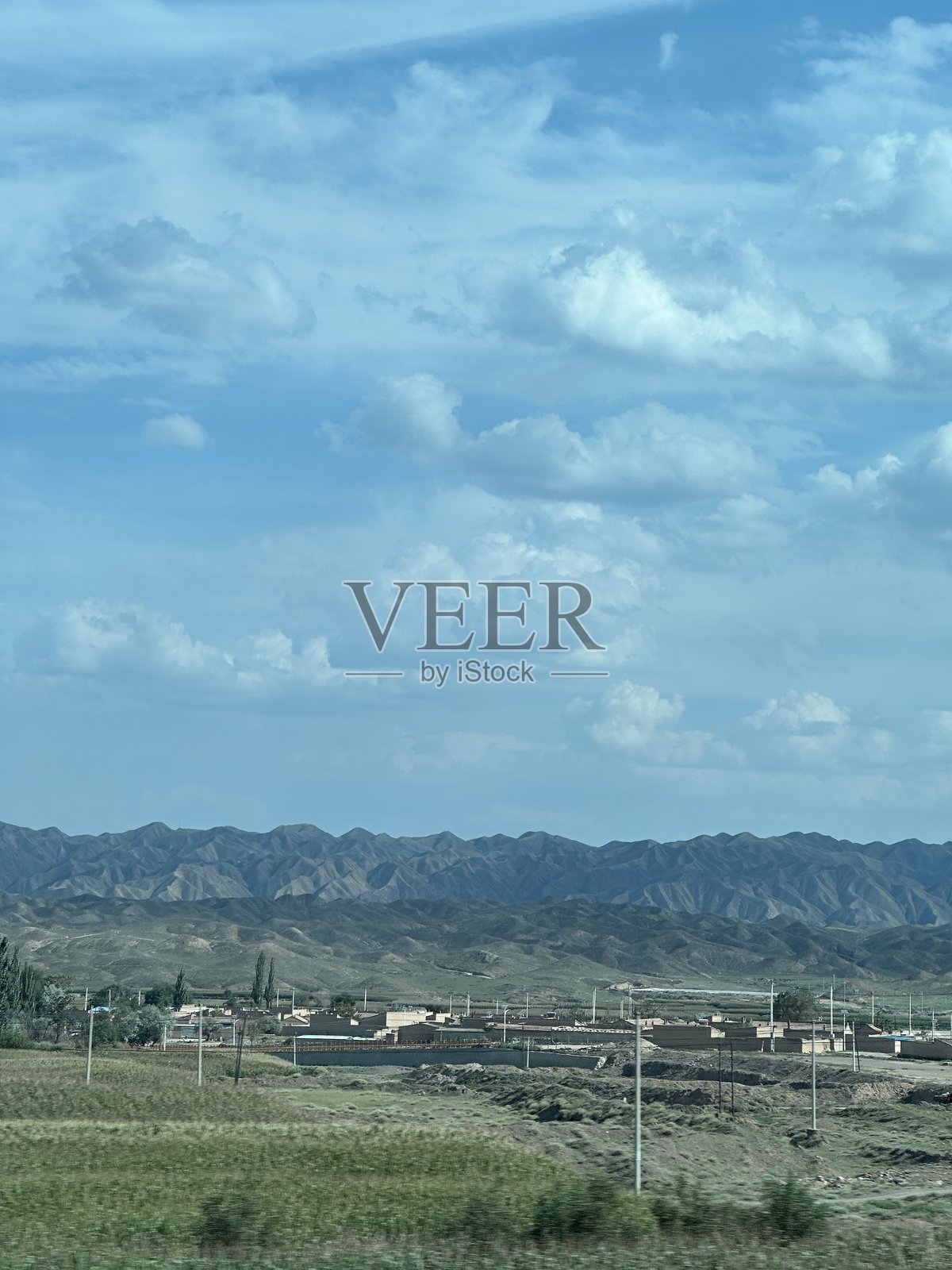 甘肃省公路沿线的戈壁风光，村庄与山脉相映成趣照片摄影图片