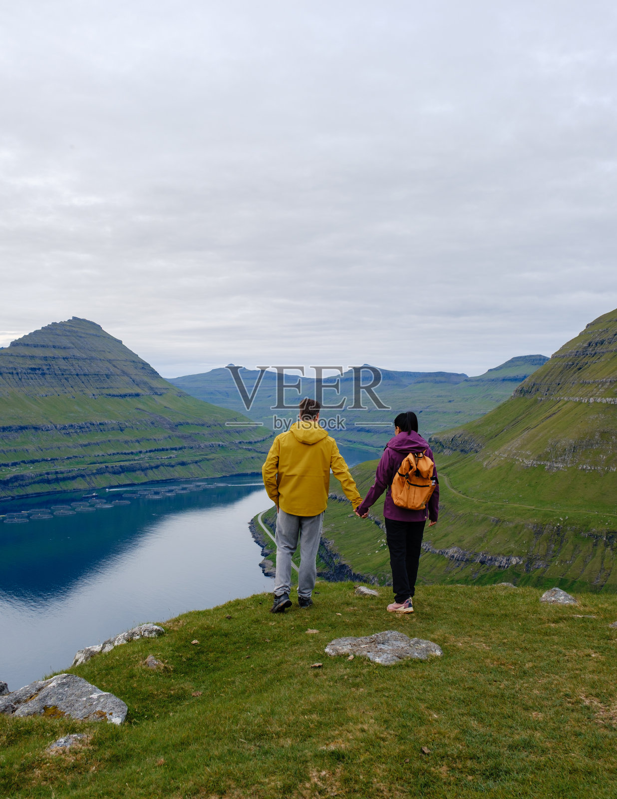 一对情侣在法罗群岛的Gonguturur Hvithamar步道上欣赏壮丽的景色照片摄影图片