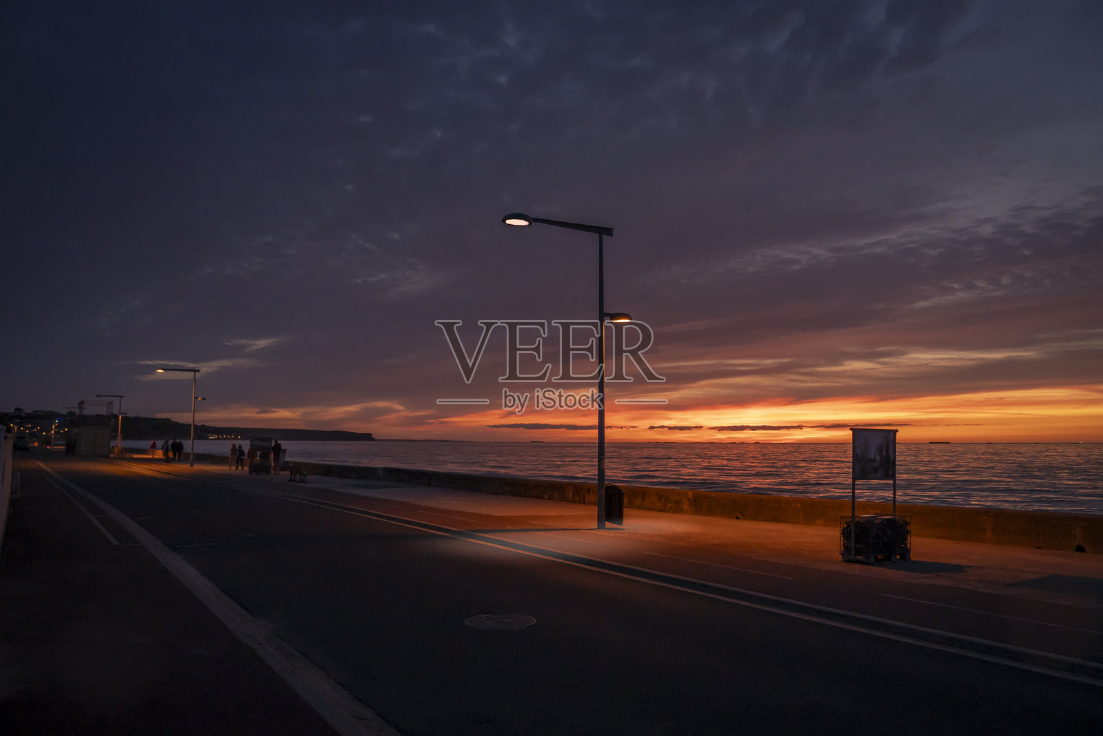 法国阿斯内尔-苏尔-梅尔 - 2025年8月8日：日落时分的码头全景，包含人群、街灯、大海和天空照片摄影图片