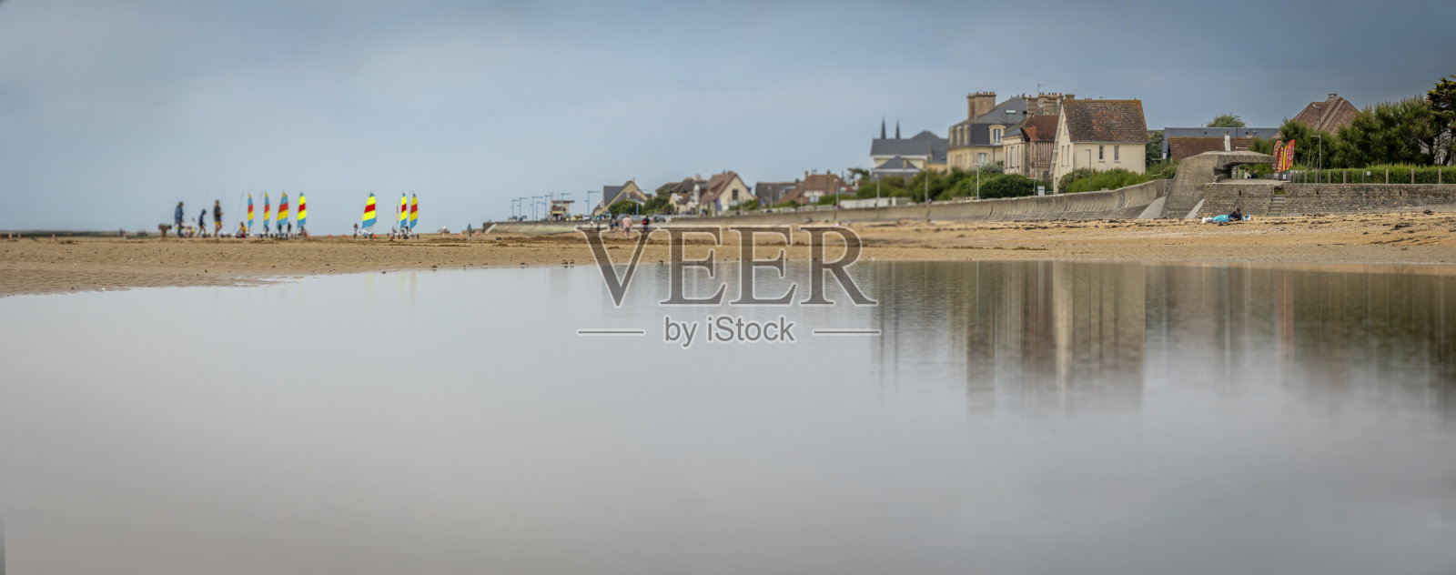 法国阿斯内尔-苏尔-梅尔 - 2025年8月8日：海滨堤坝的全景，房屋倒映在海面上，沙滩和沙地上的陆地游艇。照片摄影图片