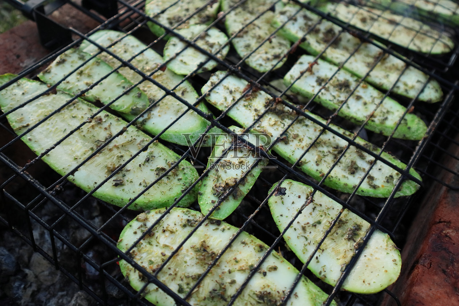 户外烧烤架上的新鲜蔬菜。切好的西葫芦和胡萝卜在火上烤制。照片摄影图片