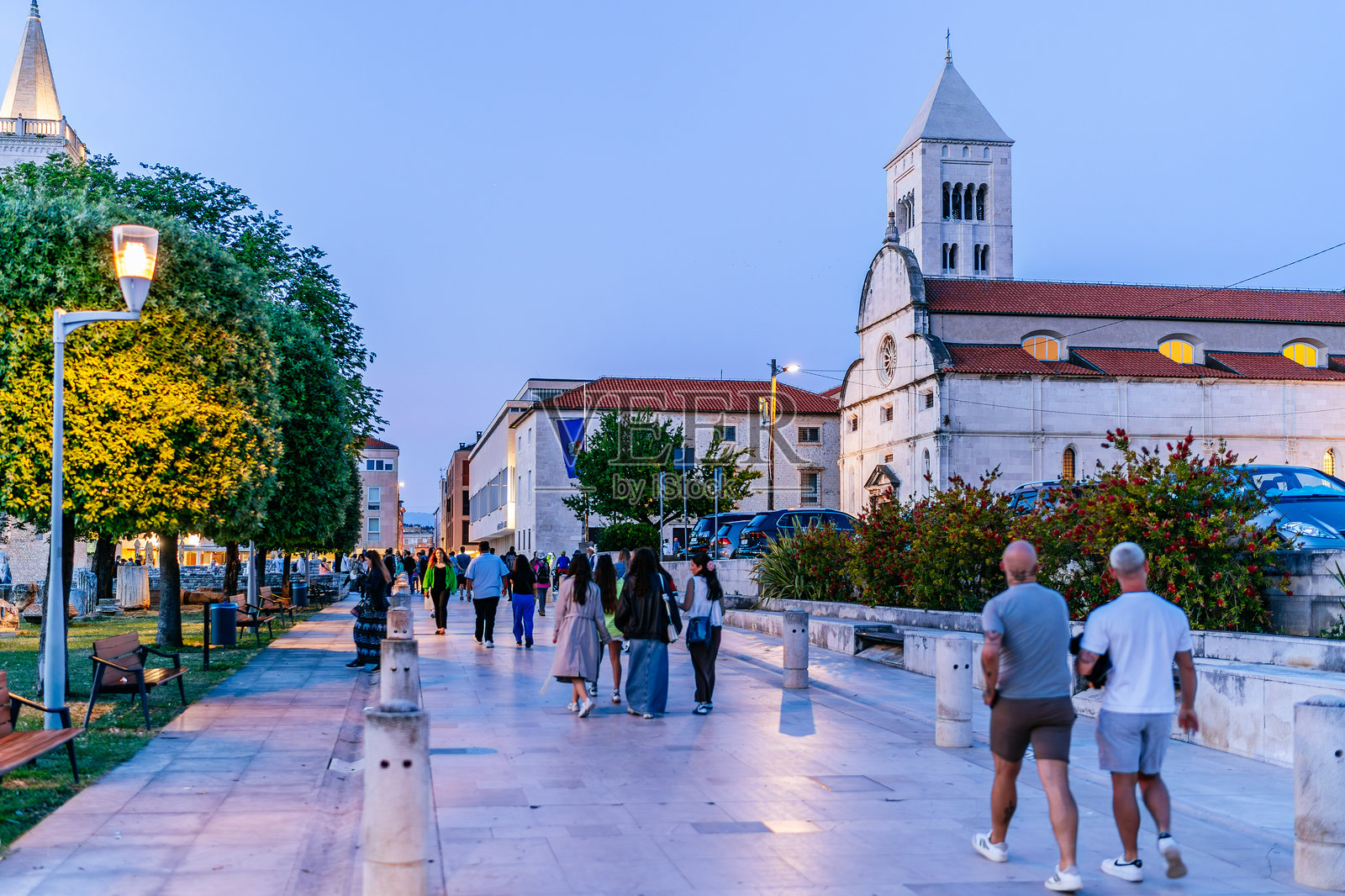 人们在黄昏时分沿着大理石街走向圣多纳图斯教堂和钟楼,位于扎达尔市中心。照片摄影图片