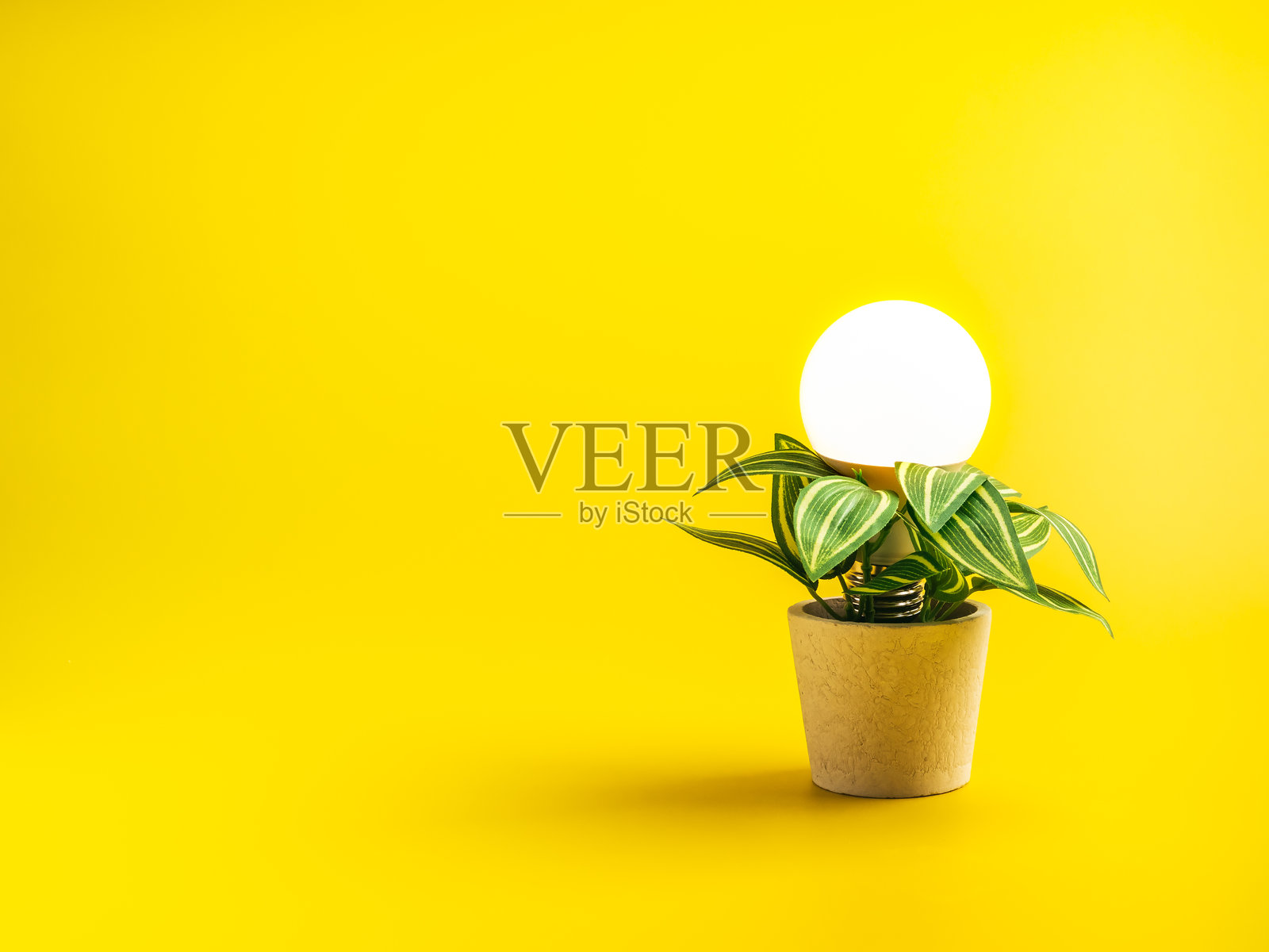 创意理念和智能增长概念，发光的灯泡从植物盆栽中生长出来，背景为黄色，留有空白，象征着创新、知识发展和智能思维。照片摄影图片