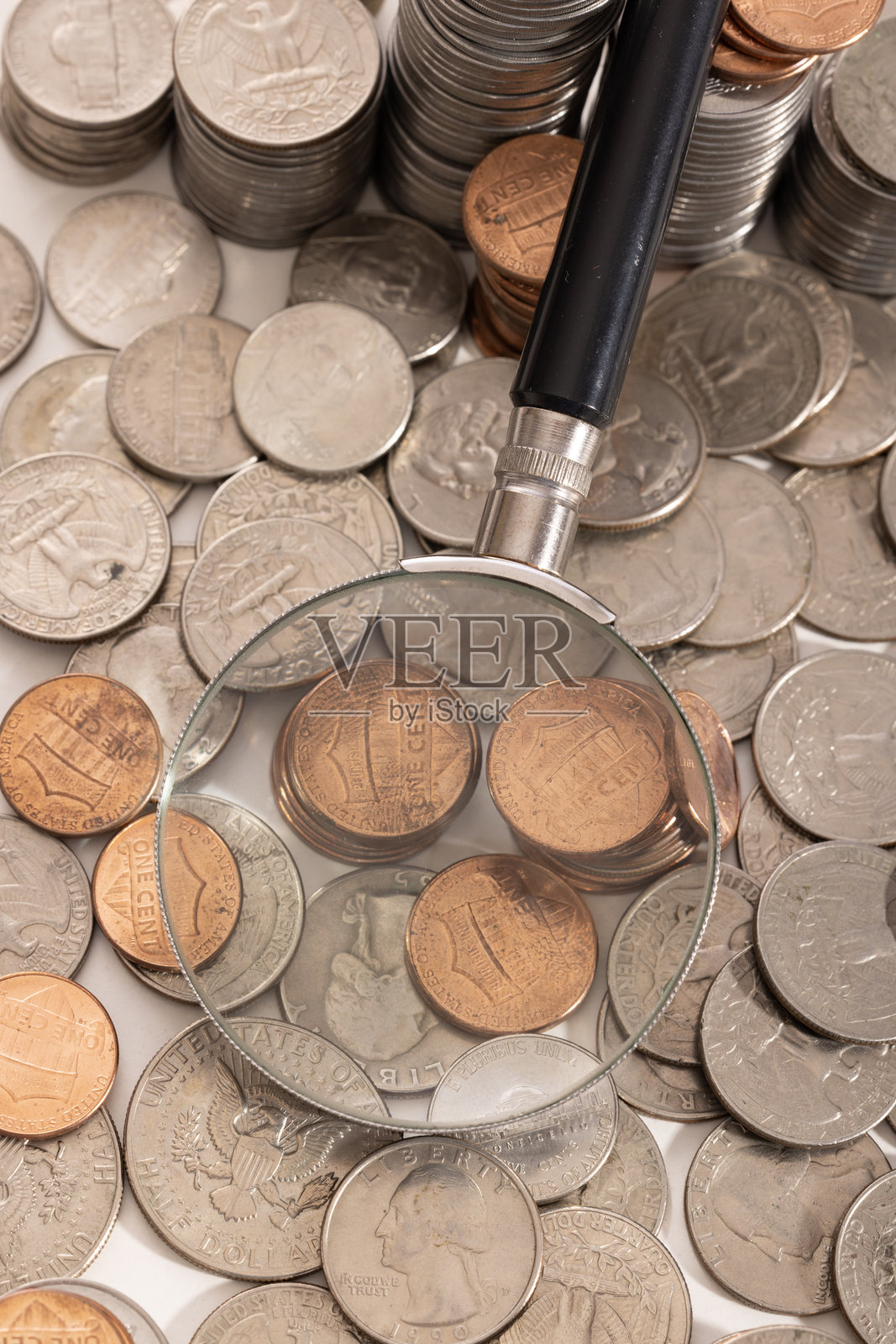 通过放大镜可以看到这枚硬币与其他各种优势的硬币小组在一起。照片摄影图片