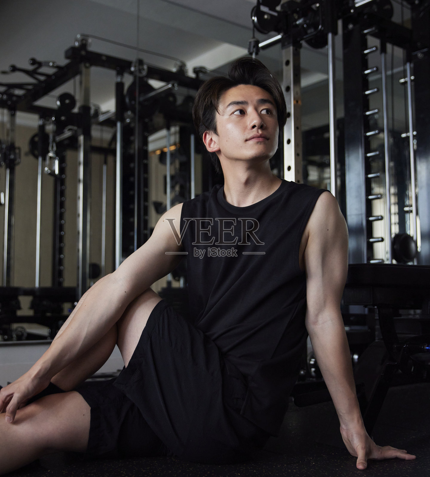 一位年轻的日本男子穿着运动服在健身房拉伸照片摄影图片