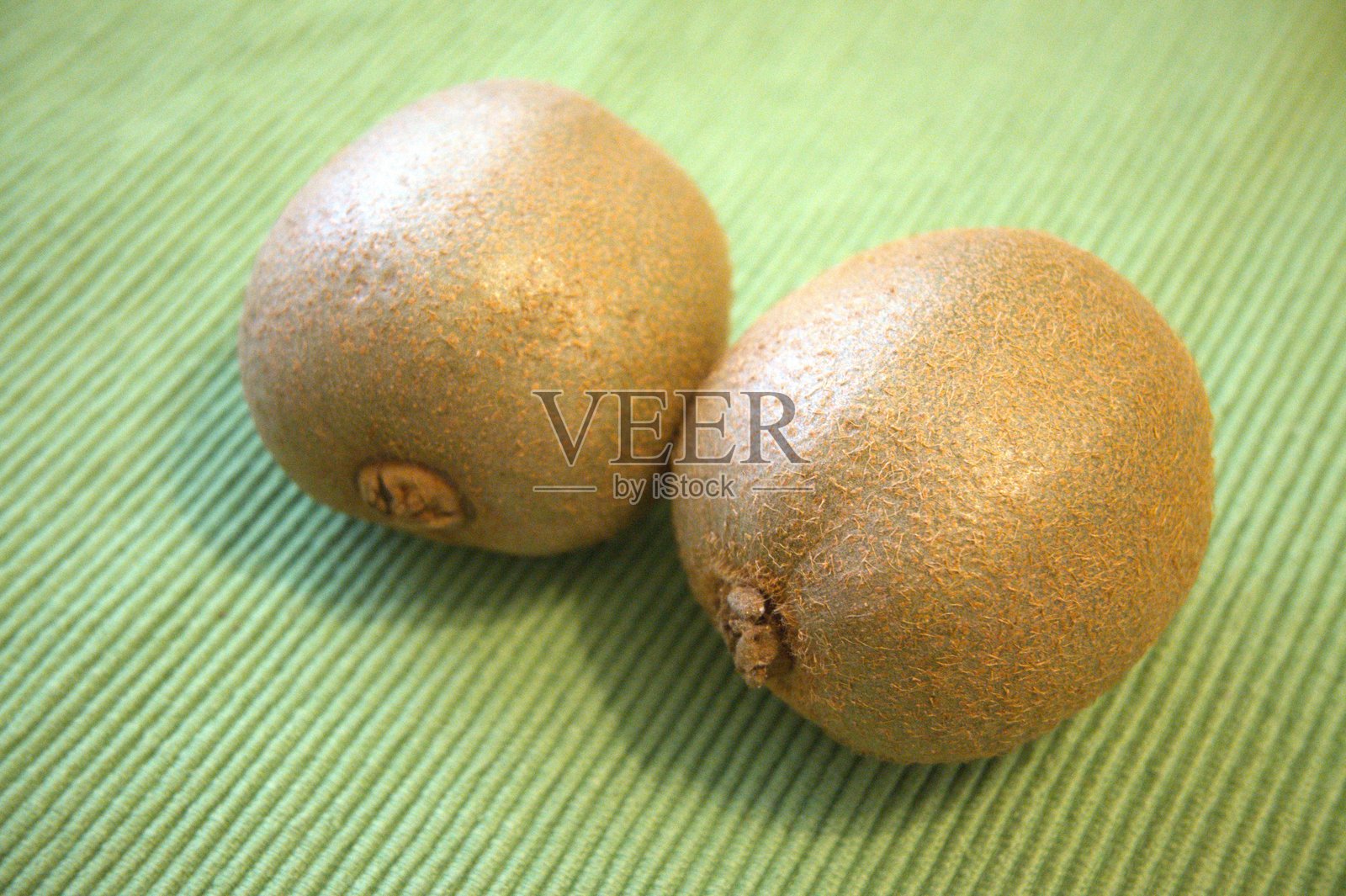 两个完整的猕猴桃在绿色背景上 - 特写，留有空白空间照片摄影图片