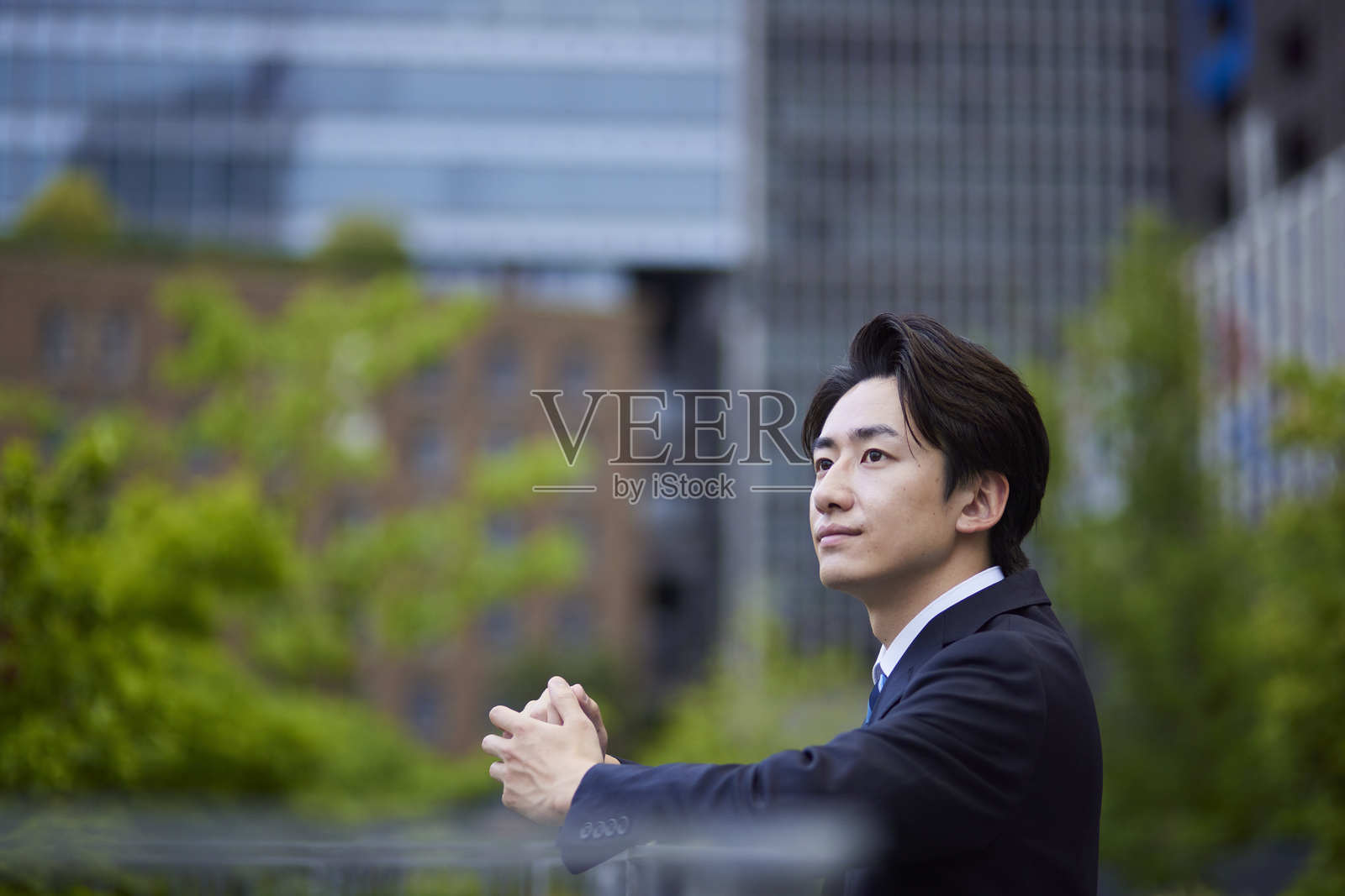 一位穿着西装的日本商人凝视远方，背景是一座建筑。照片摄影图片