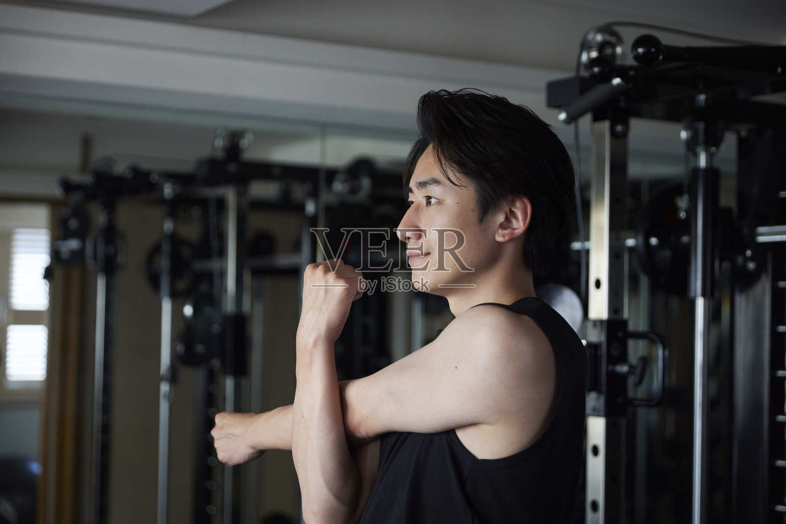 一位年轻的日本男子穿着运动服在健身房拉伸照片摄影图片