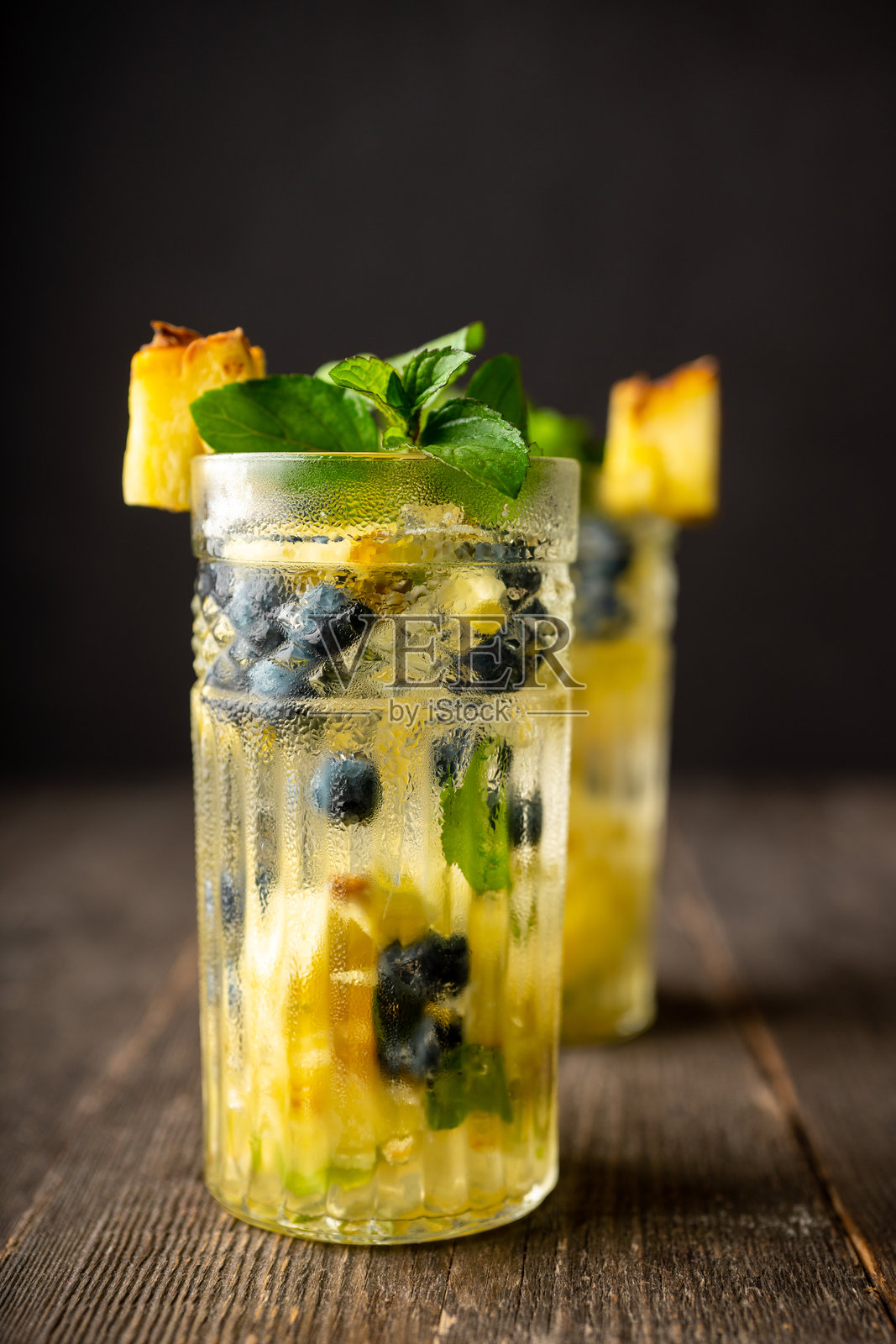 清新的莫吉托鸡尾酒，搭配菠萝和蓝莓，背景为乡村风格照片摄影图片