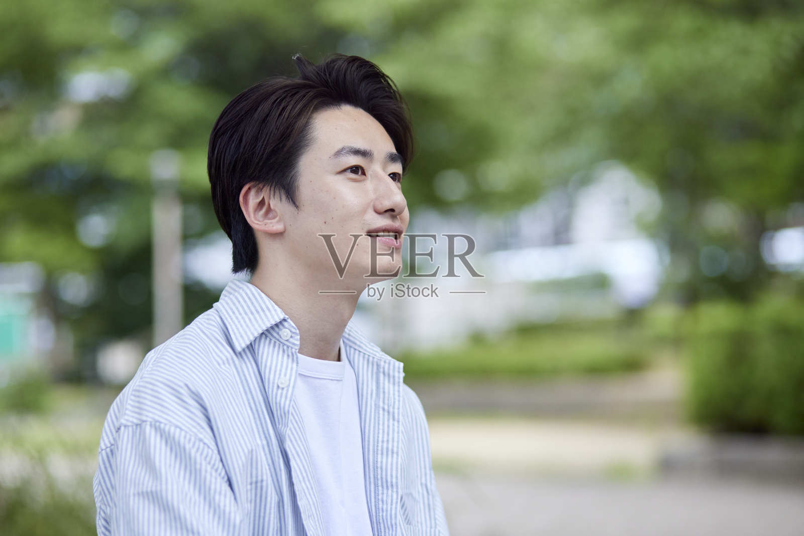 一位微笑的年轻日本男子在公园里放松，享受他的休息日照片摄影图片