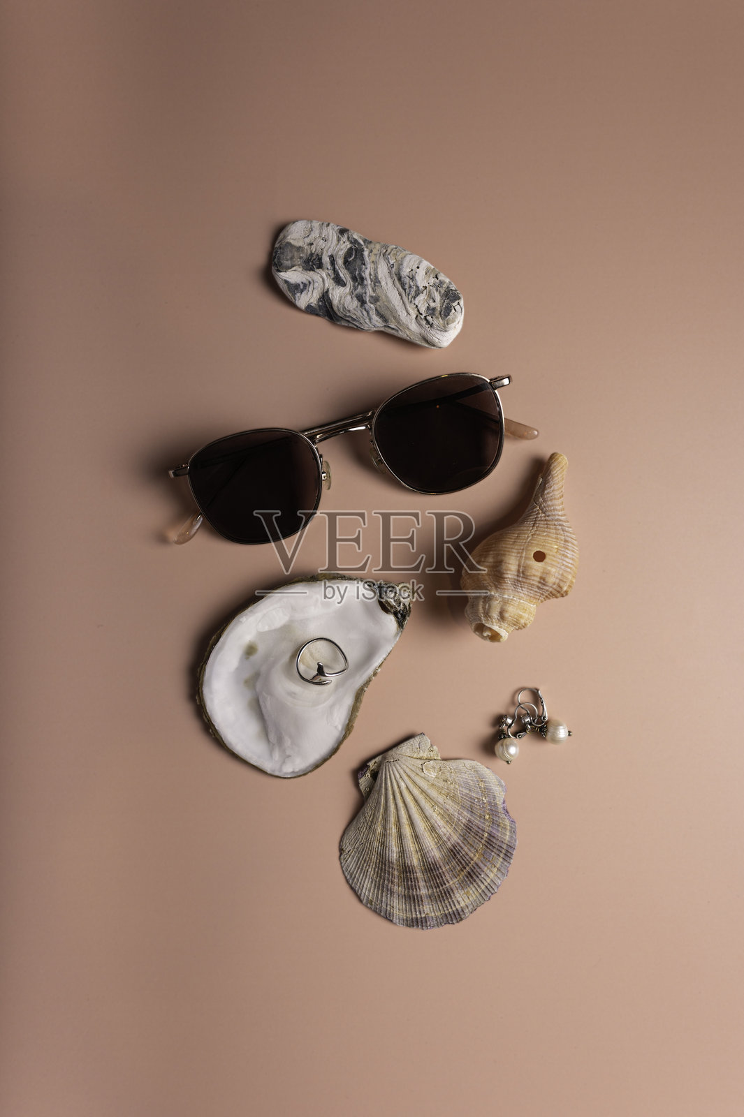 海滩灵感的平铺图，配有太阳镜、海贝和珠宝，背景为桃色照片摄影图片