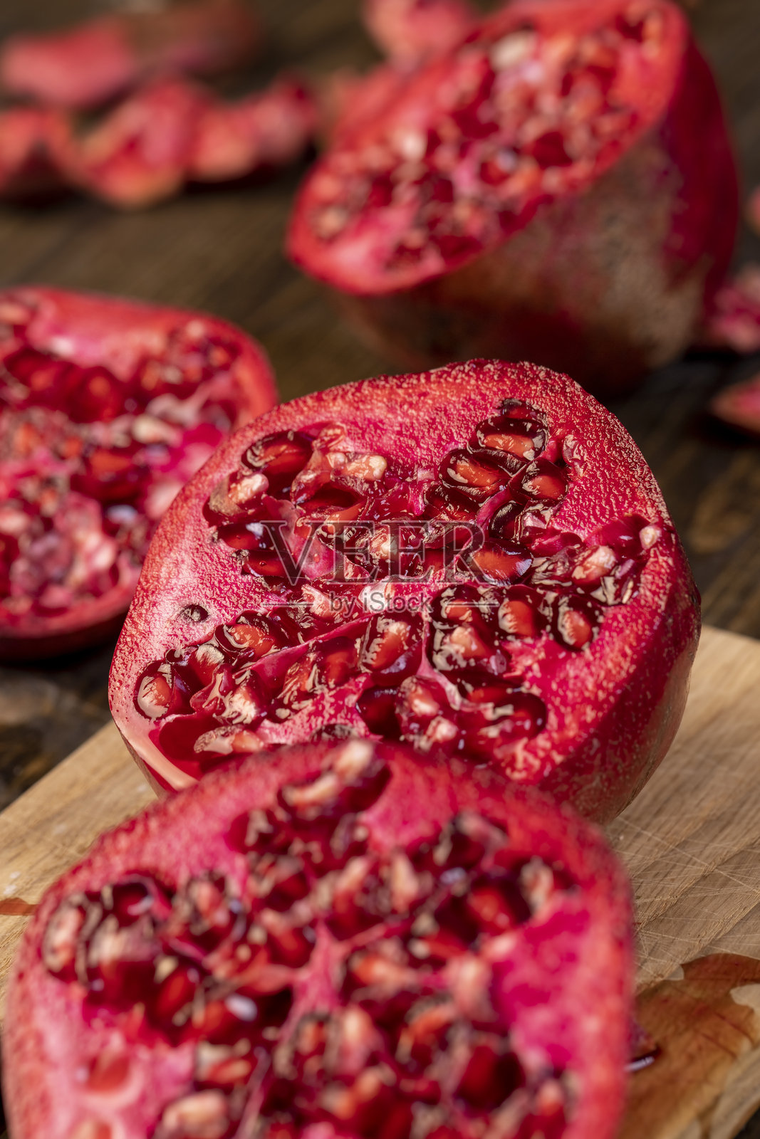 切开的石榴放在桌子上，甜美的红色石榴在烹饪过程中切成块。照片摄影图片
