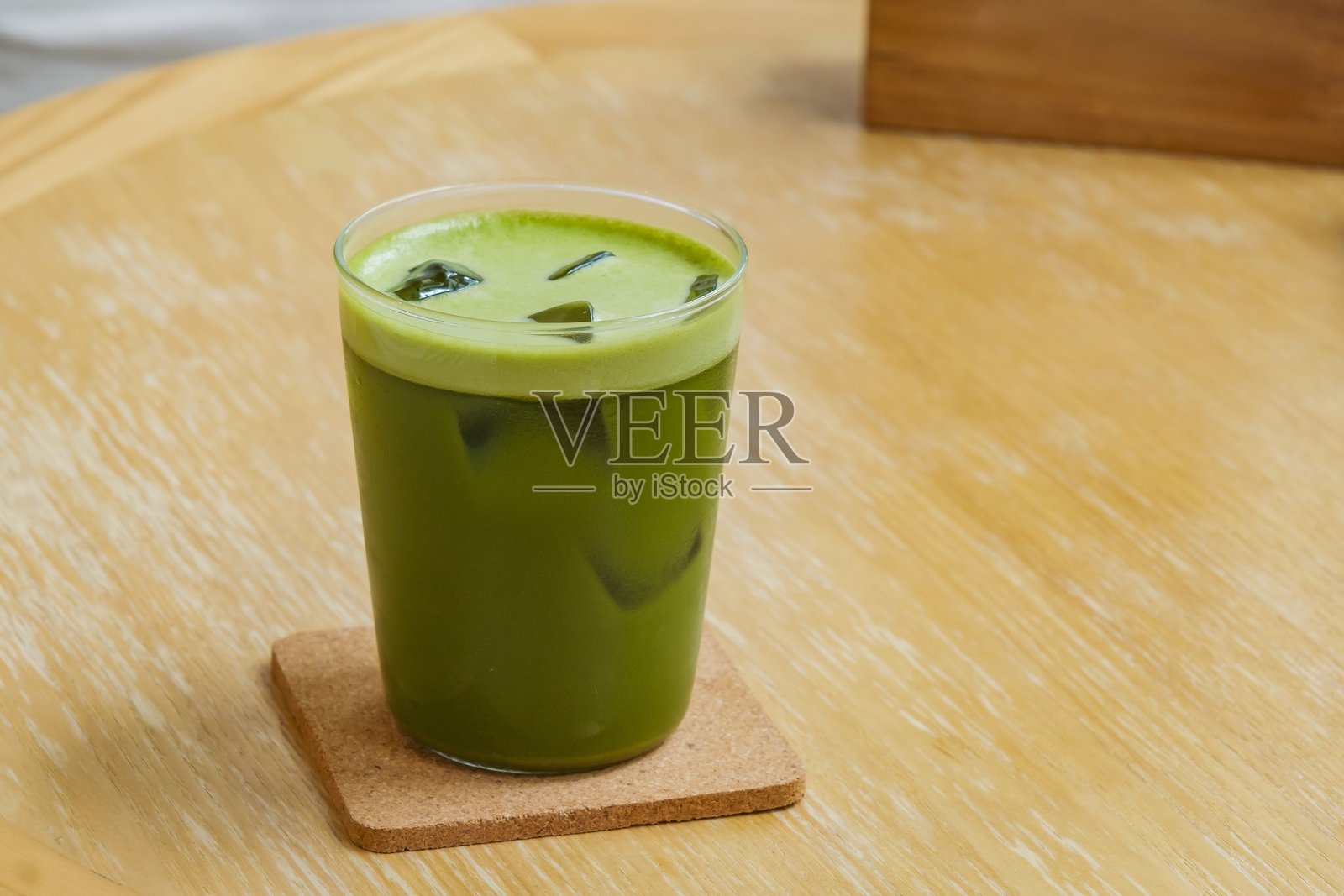 新鲜生动的绿色冰抹茶，摆放在木桌上，旁边有绿色观赏植物，咖啡馆内的场景。照片摄影图片