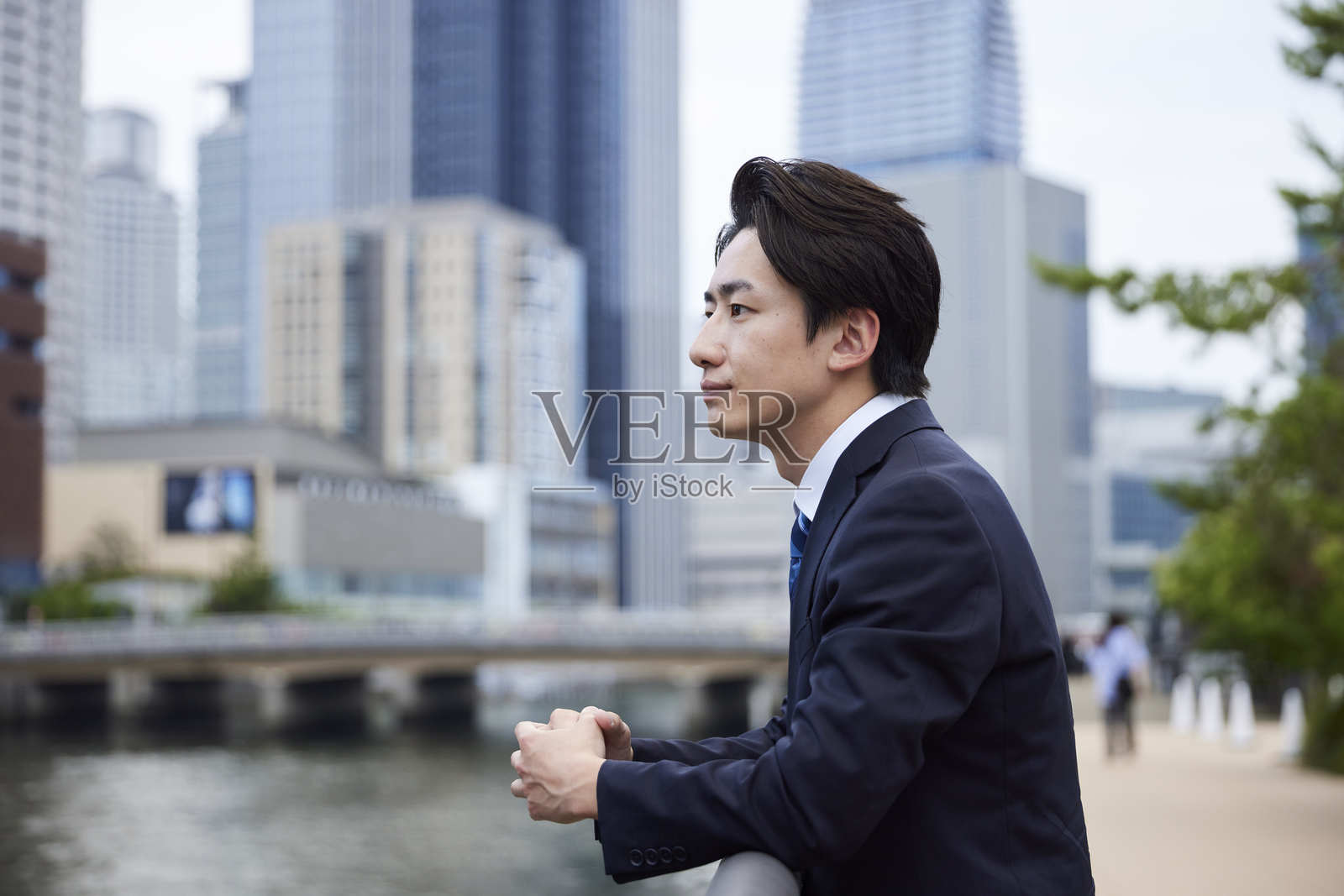 一位身穿西装的日本商人凝视远方，背景是一座建筑。照片摄影图片