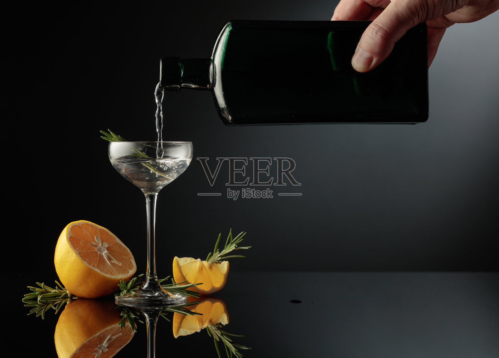 黑色反光背景上的柠檬迷迭香琴酒。照片摄影图片