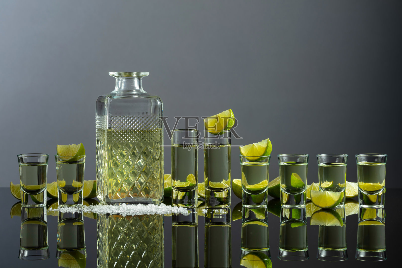 灰色背景上的龙舌兰酒、青柠片和盐的酒杯。照片摄影图片