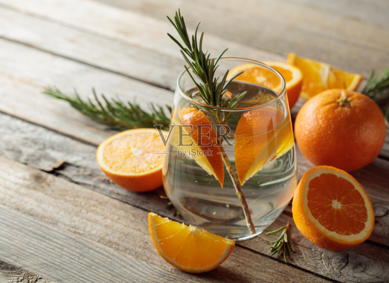 在旧木桌上放着冰块、迷迭香和橙片的硬气泡酒。照片摄影图片