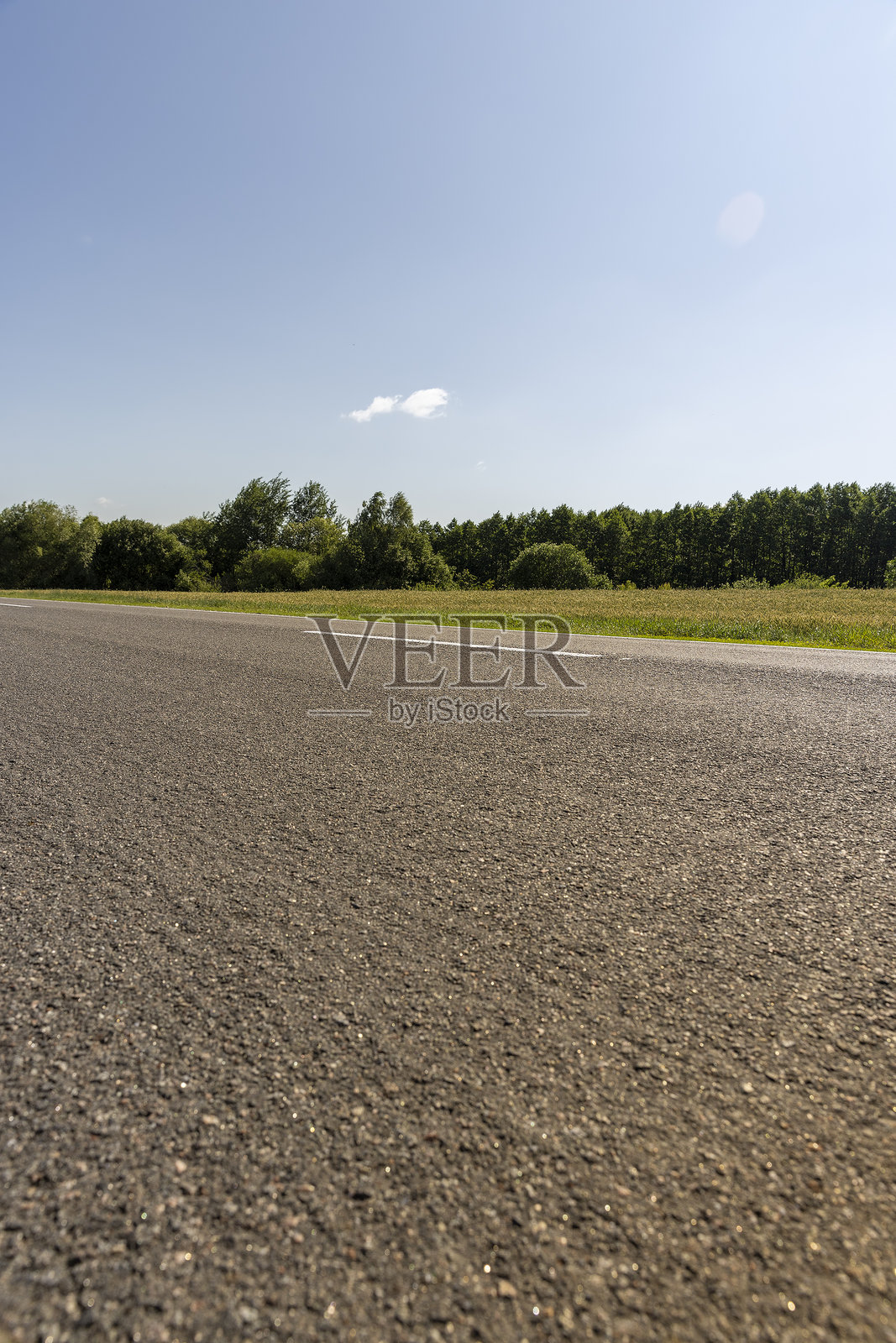 阳光明媚的白天，车辆通行的道路，白色路标，蓝天。照片摄影图片