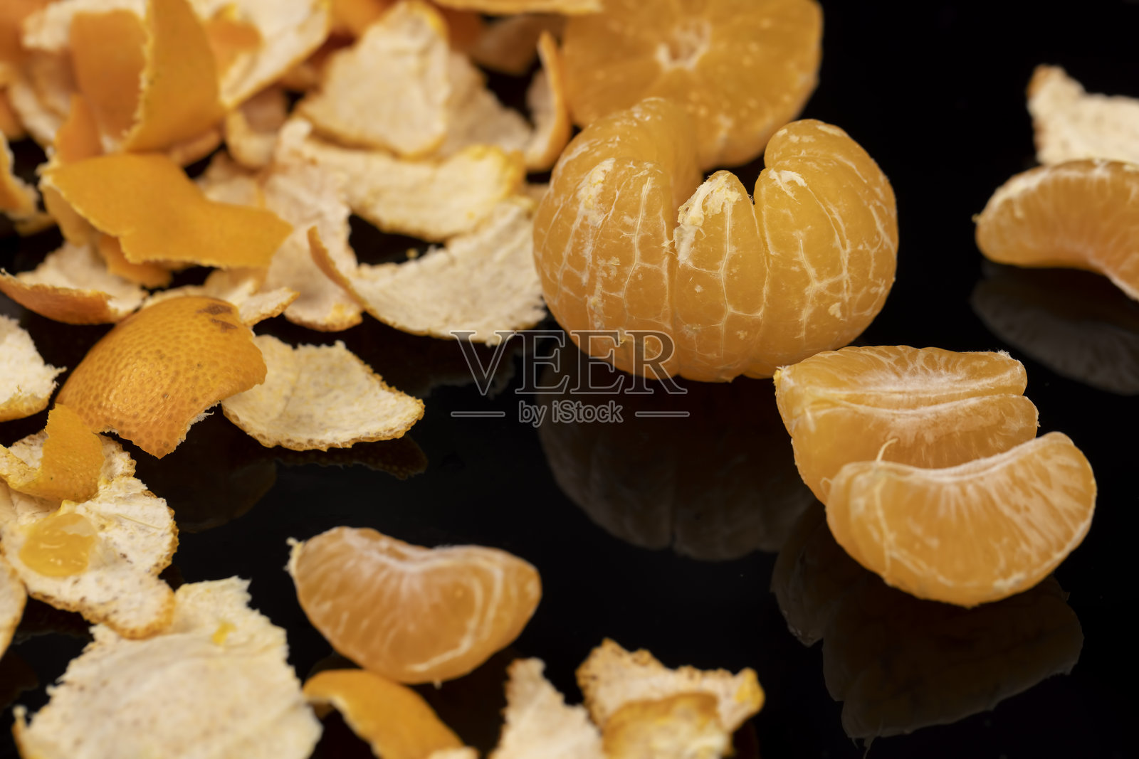 橘子的倒影在镜面上，剥皮的多汁橘子放在镜子上，特写镜头照片摄影图片