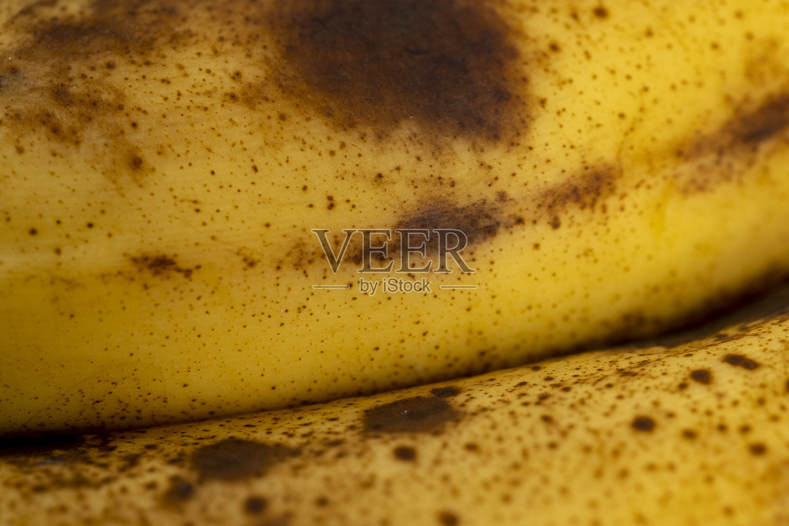 黑松木桌子上的香蕉特写，一根老化腐烂的熟香蕉，颜色从黄色变为黑色。照片摄影图片