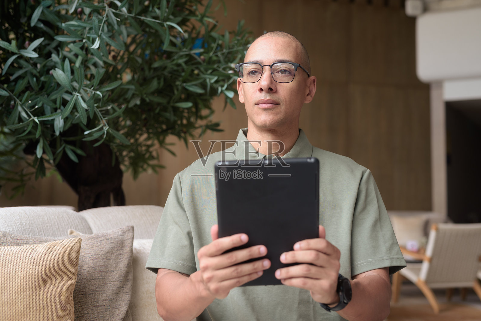 拉丁裔成年男子在酒店休息室或酒吧使用平板电脑，专注于旅行生活方式和科技。照片摄影图片