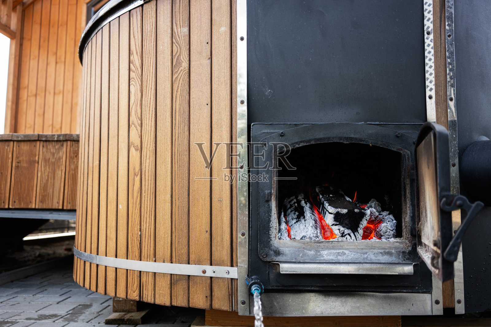 带有可见炉子和内部发光火焰的木质户外热水浴缸照片摄影图片