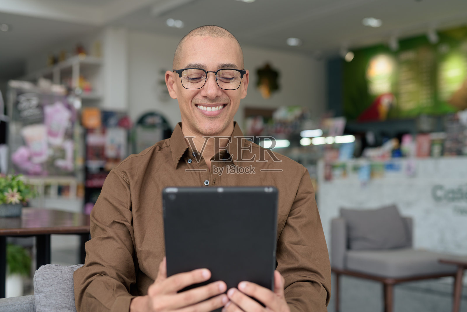 意大利男子在咖啡馆使用平板电脑，戴着眼镜，穿着衬衫，展现自信的现代生活方式照片摄影图片