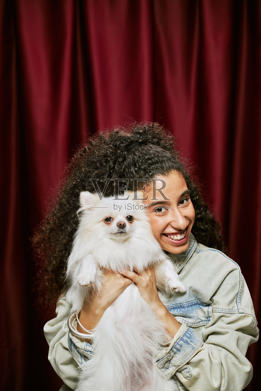 微笑着抱着毛茸茸狗狗的中东年轻女性肖像照片摄影图片