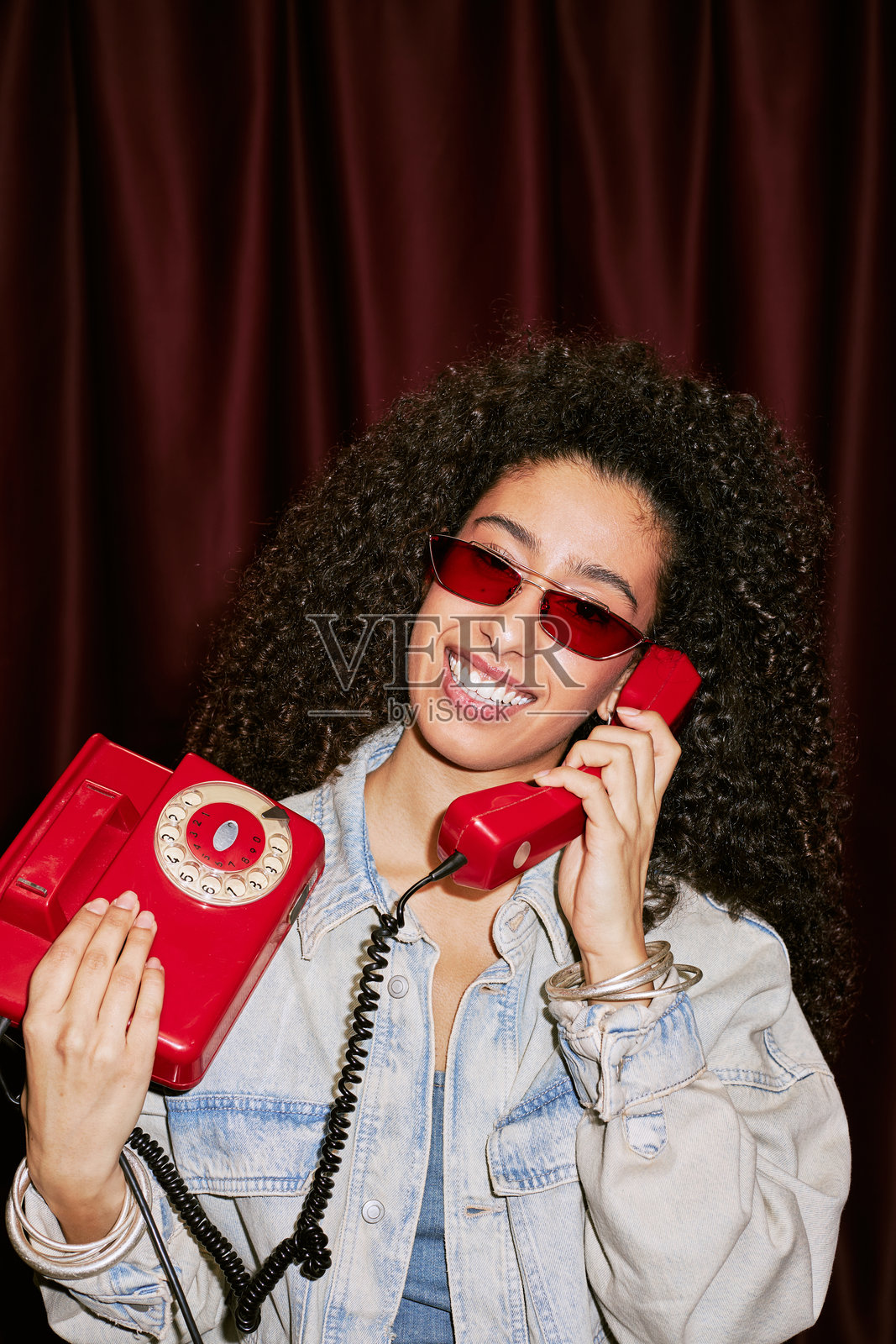 年轻的混血女性微笑着拿着复古电话的肖像照片摄影图片