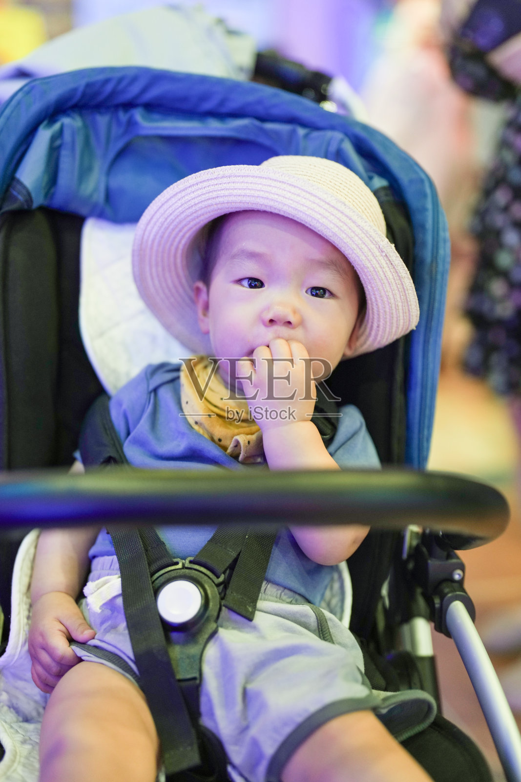 在一个老街风格的购物中心，一家中国家庭聚在一起，一个一岁的婴儿坐在婴儿车里，沐浴在柔和的蓝色灯光中，柔化了附近的木质外立面和灯笼。中国上海。春天。照片摄影图片