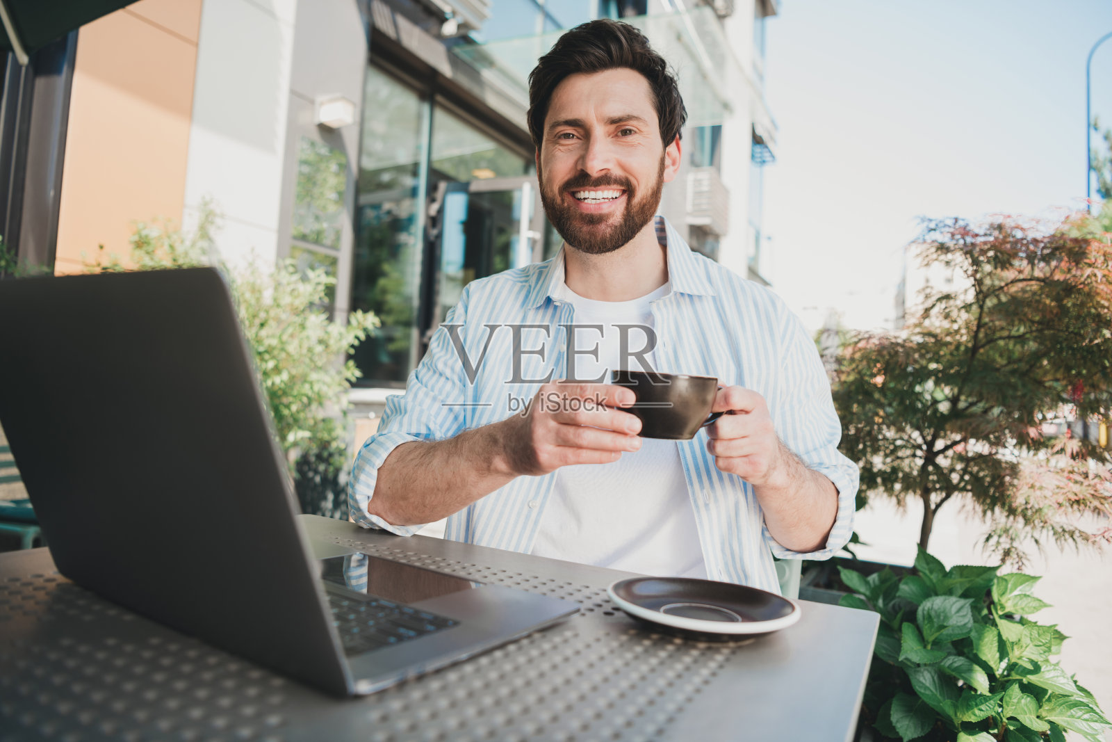 帅气的年轻人在城市咖啡馆户外工作时享受咖啡休息。照片摄影图片