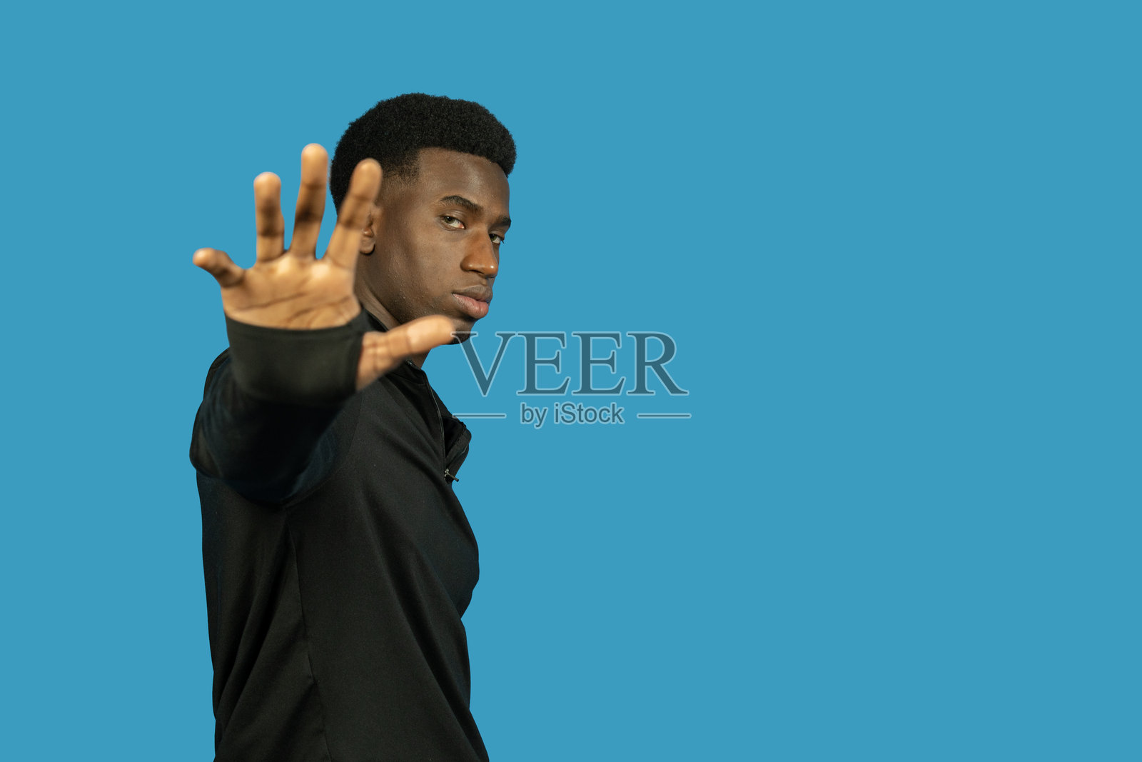 年轻男子在蓝色背景上用手做出停止手势照片摄影图片