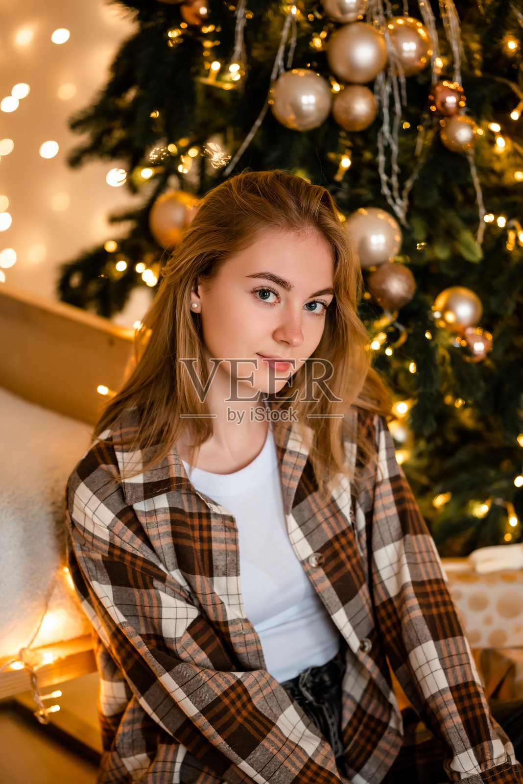 女人在装饰华丽的圣诞树旁放松照片摄影图片