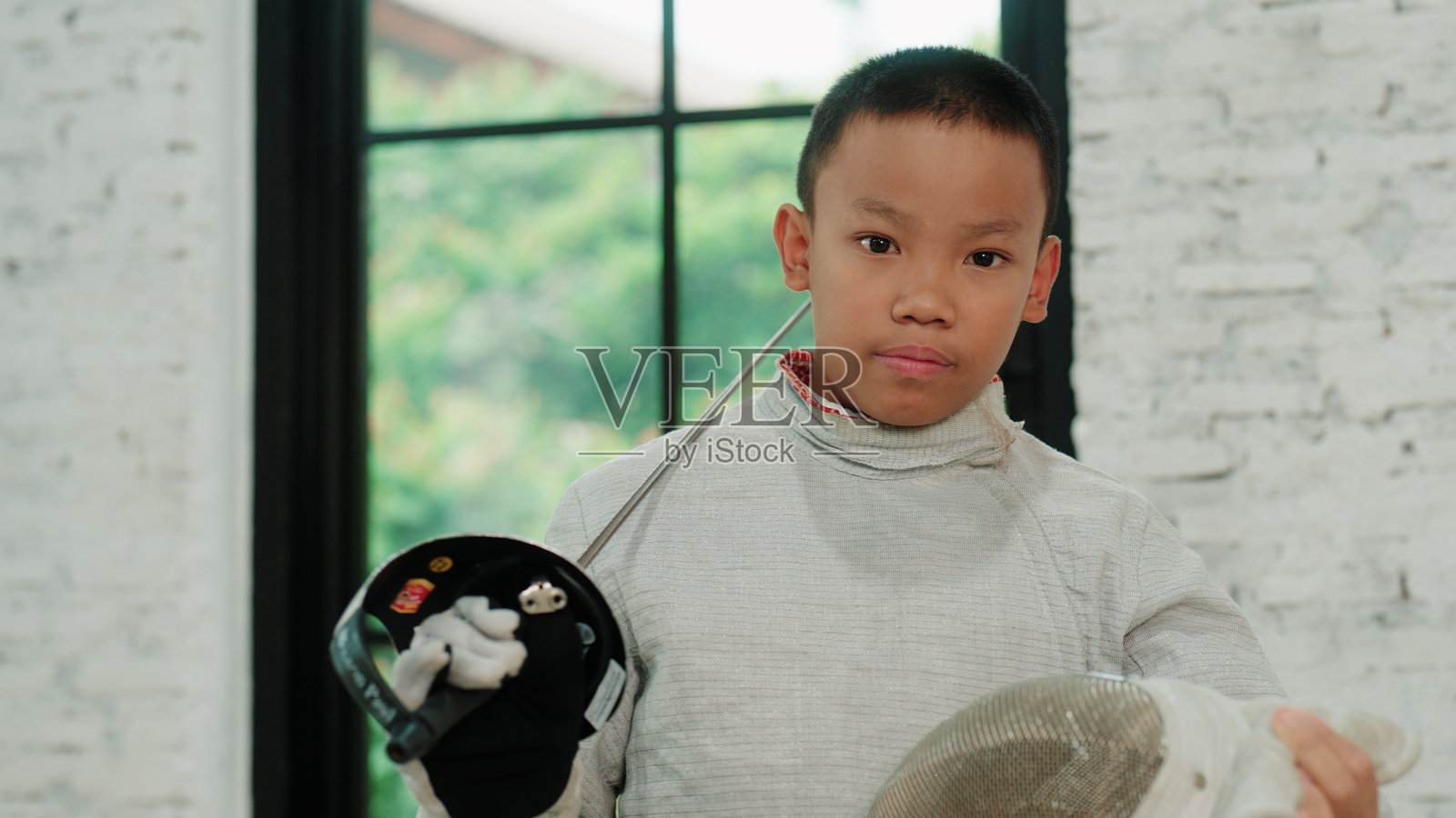 年轻男孩击剑手摘下击剑面罩，朝镜头看去的肖像照片摄影图片