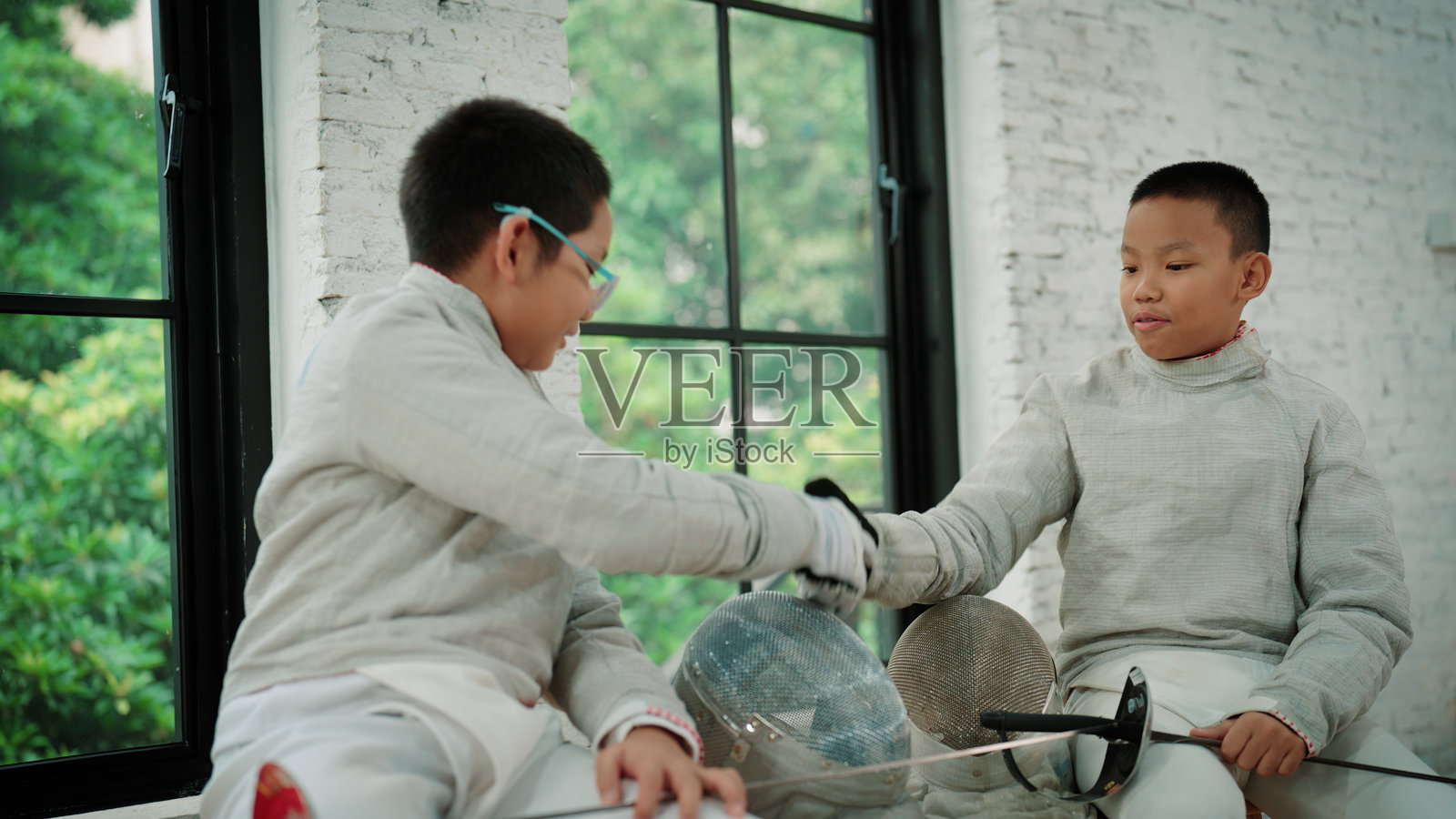 两名年轻的击剑手戴着手套互相问候，准备开始比赛照片摄影图片