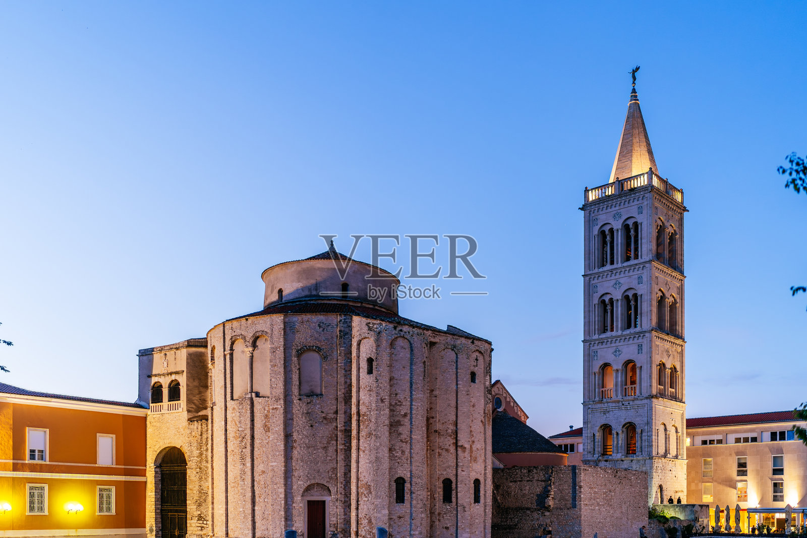 扎达尔老城的圣多纳图斯教堂，石墙和高耸的钟楼在蓝色的黄昏天空下熠熠生辉。照片摄影图片