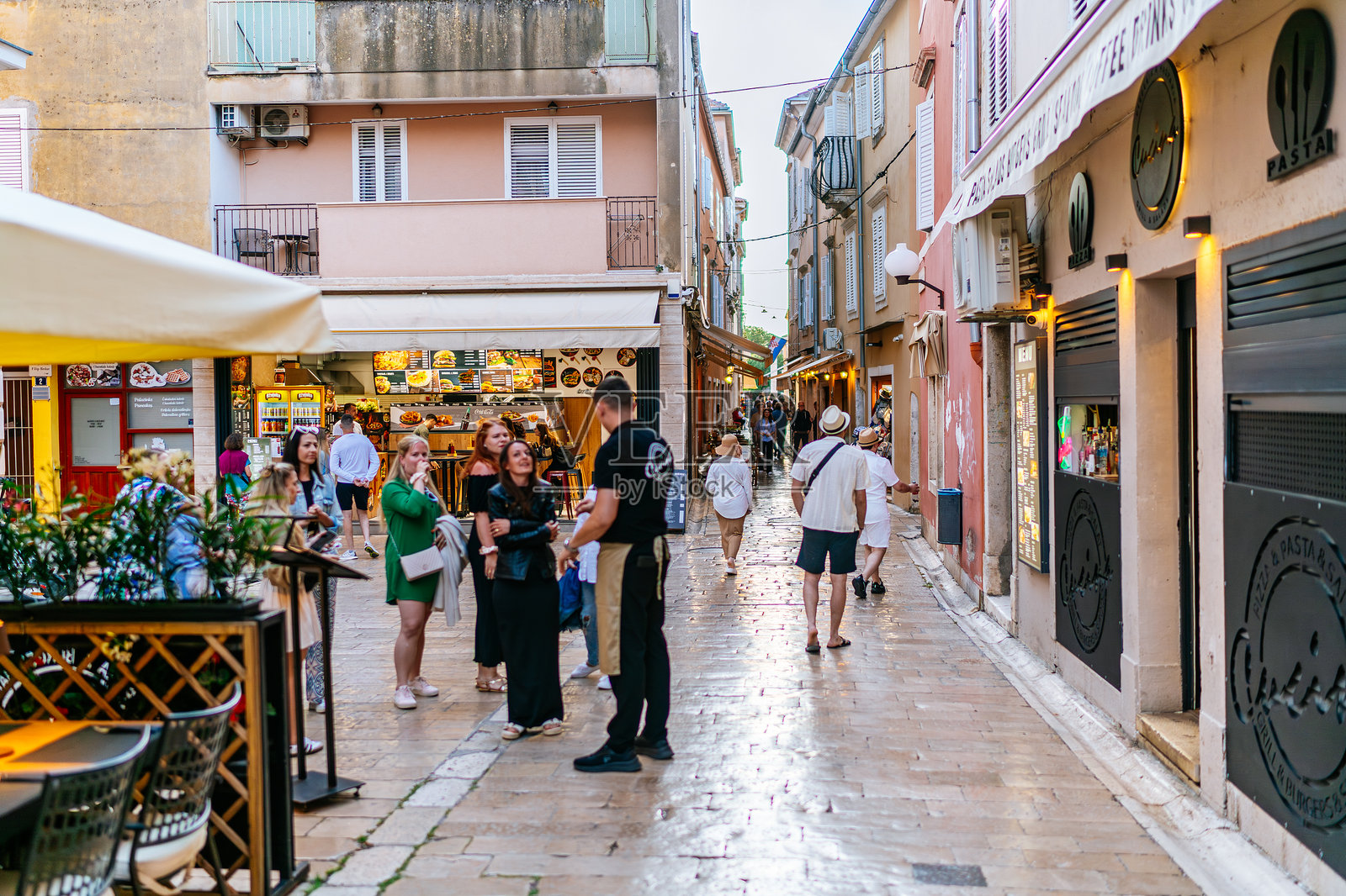 扎达尔老城繁忙的购物街，行人和骑自行车的人在现代石铺人行道上穿行照片摄影图片