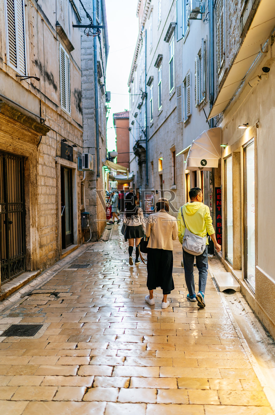 扎达尔老城狭窄石巷的傍晚景色，人们在高耸的历史建筑之间漫步照片摄影图片