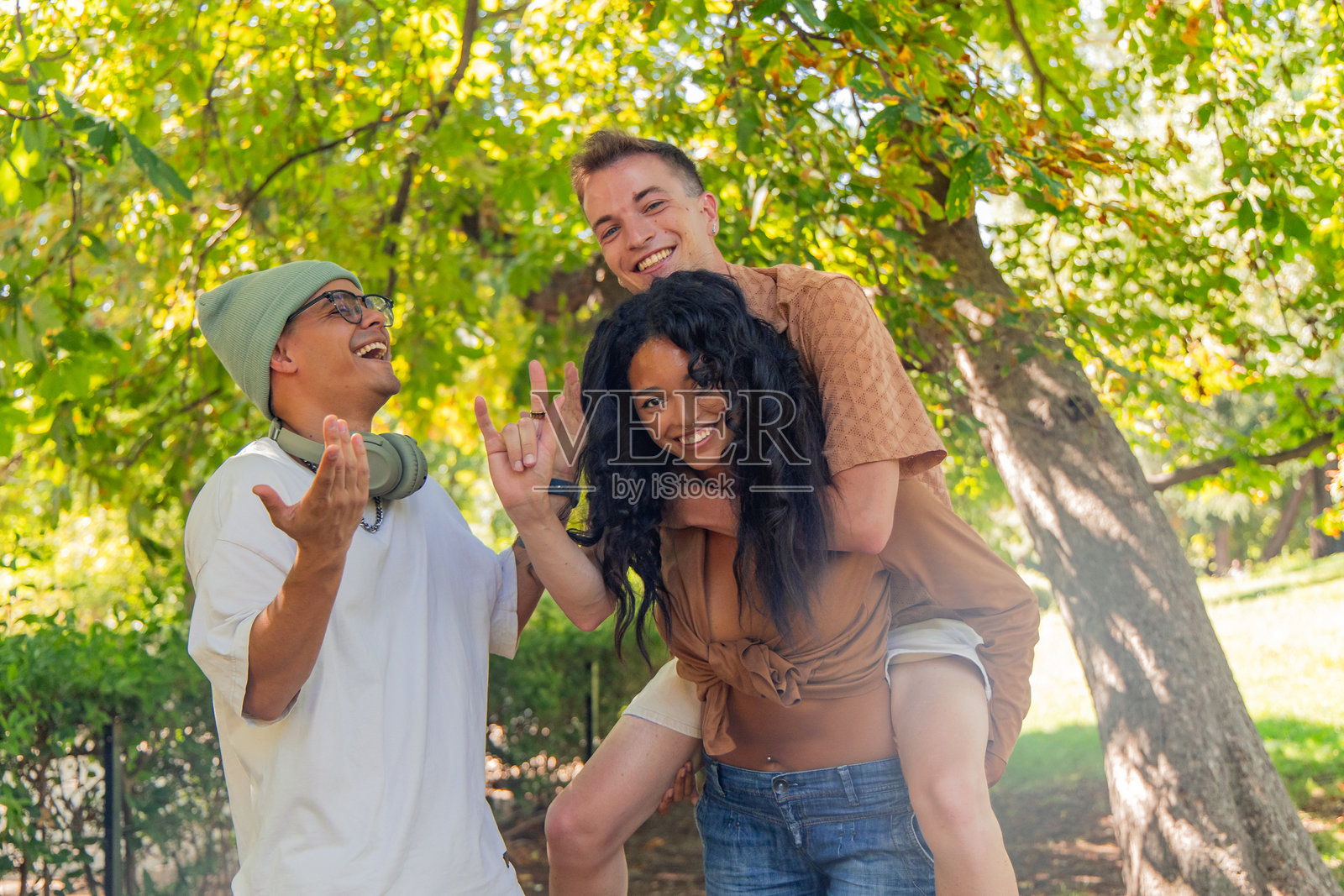 多种族的年轻朋友在公园里玩得开心，互相背着对方。照片摄影图片