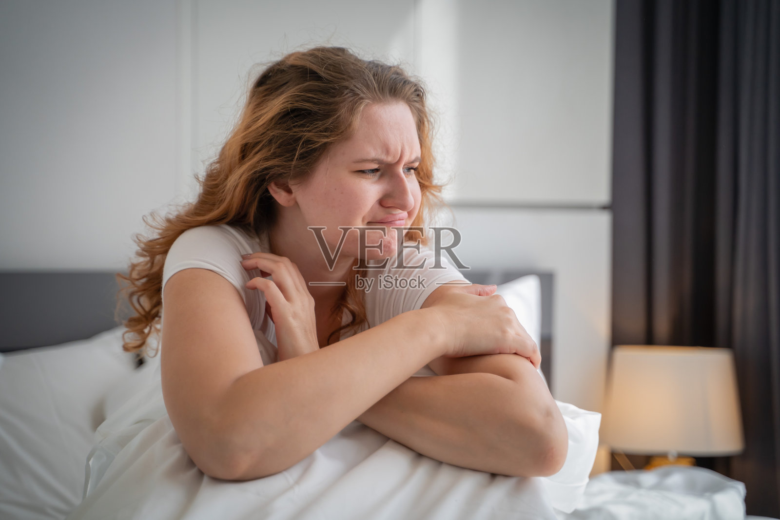 一位年轻女性感到困倦和不适，不想在早晨醒来。照片摄影图片